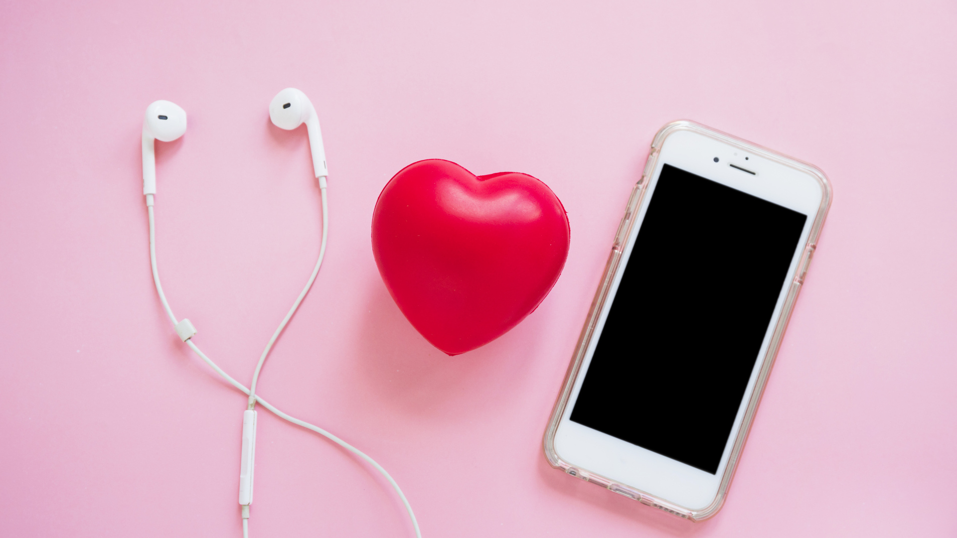 Телефон, наушники и красное сердце на розовом фоне
