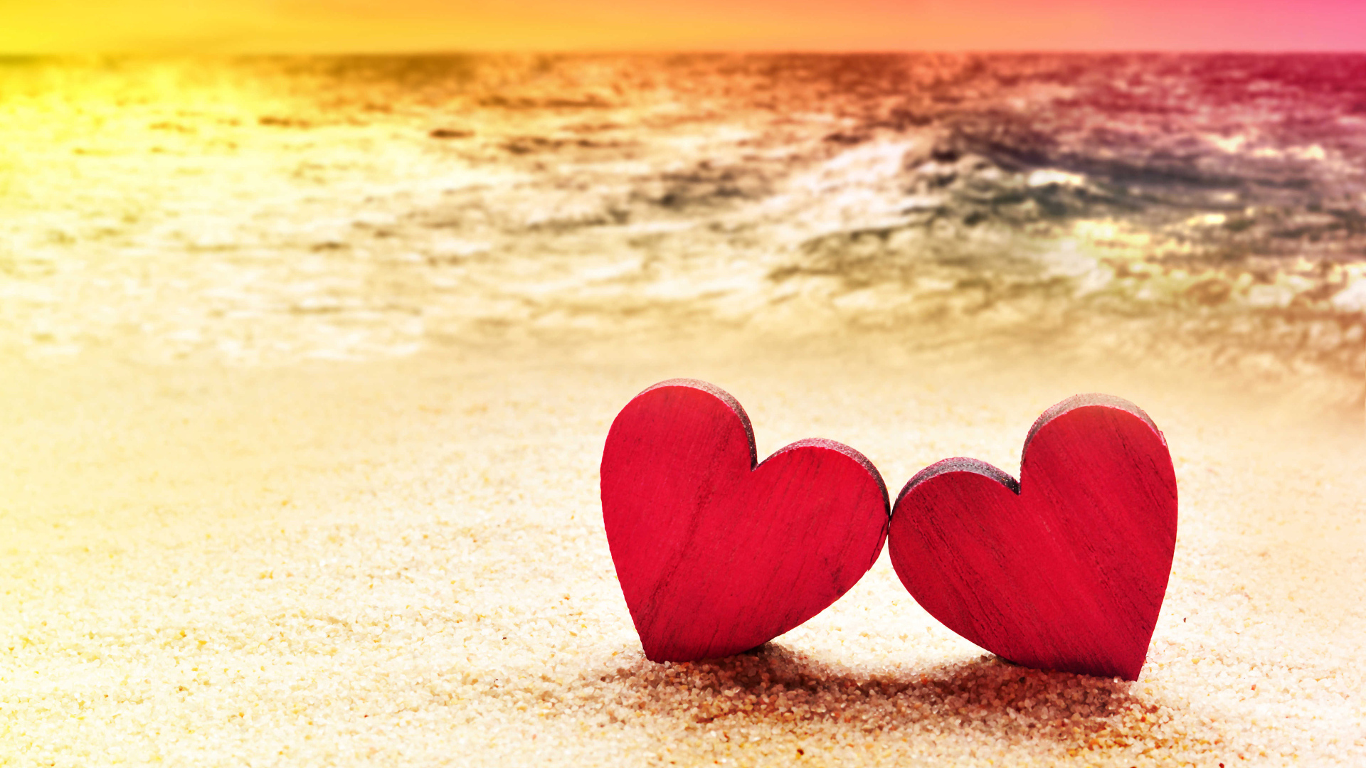 Два красных сердечка на песке на пляже