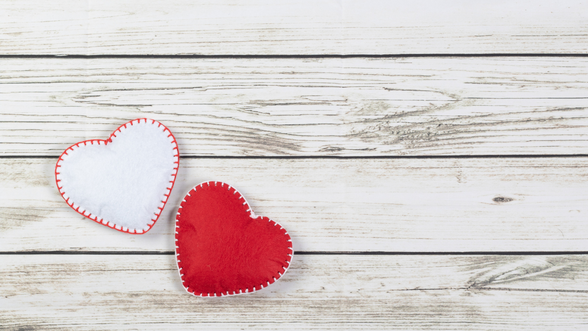 Белое и красное сшитое сердце на деревянном фоне
