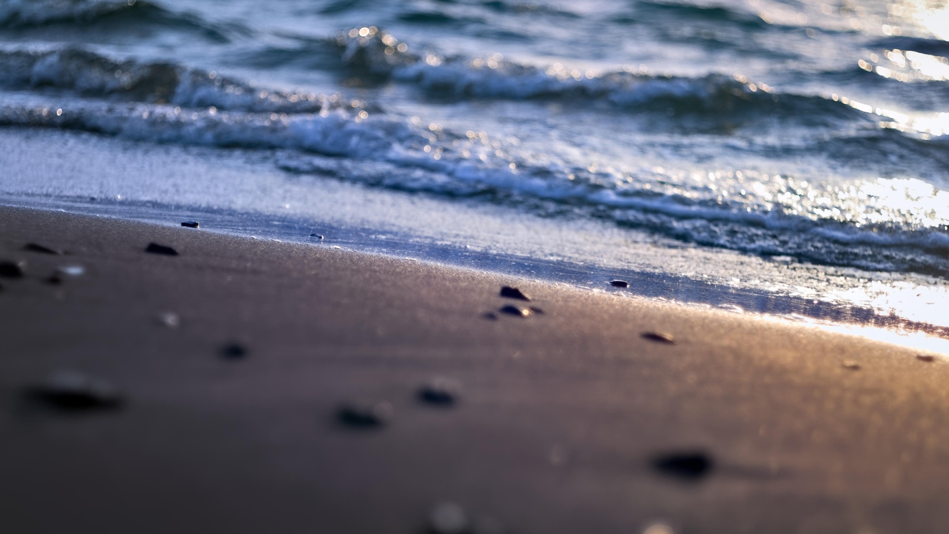 Мокрый морской песок омывает вода