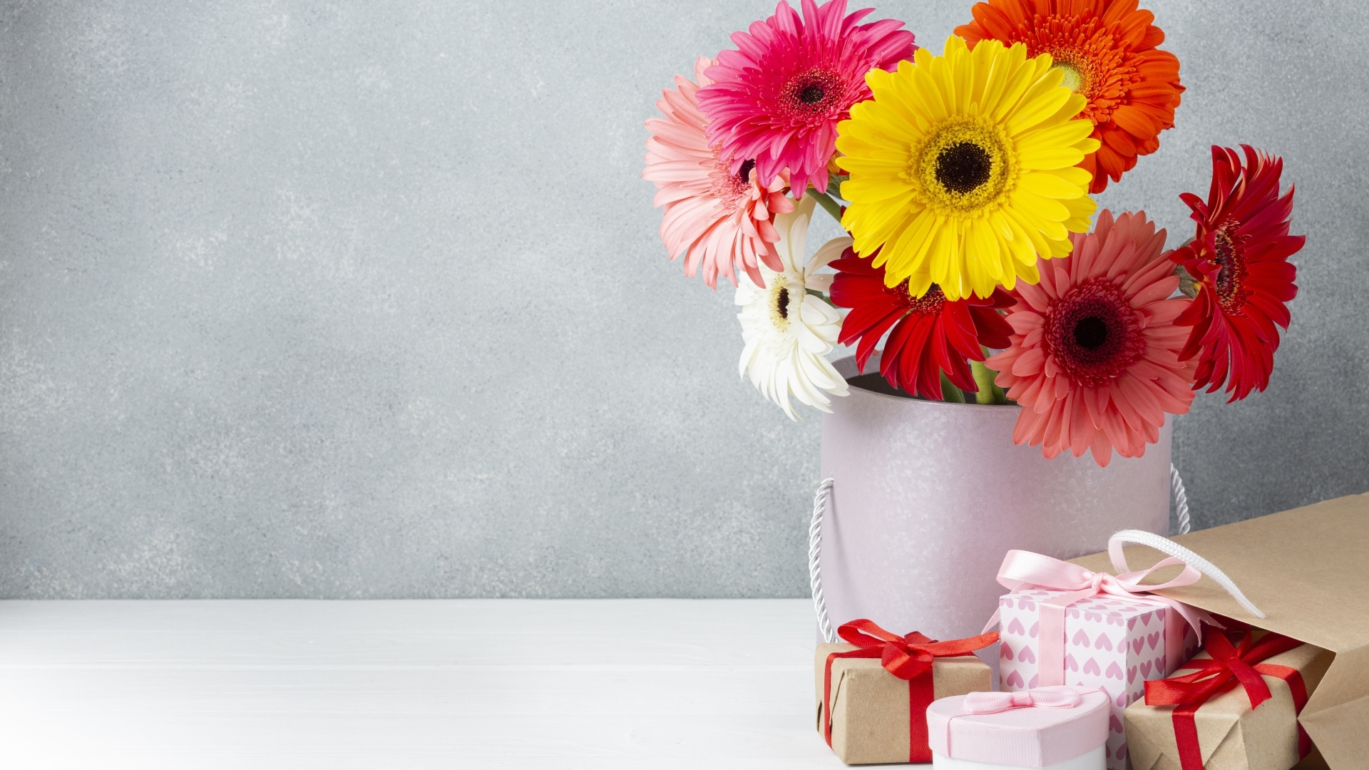 Букет разноцветных цветов герберы на столе с подарками