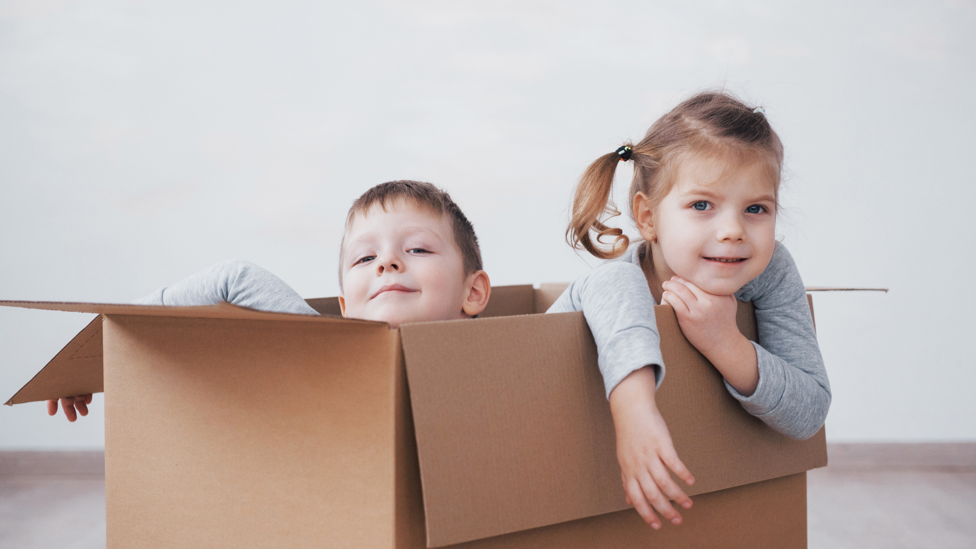 Брат и сестра сидят в картонной коробке