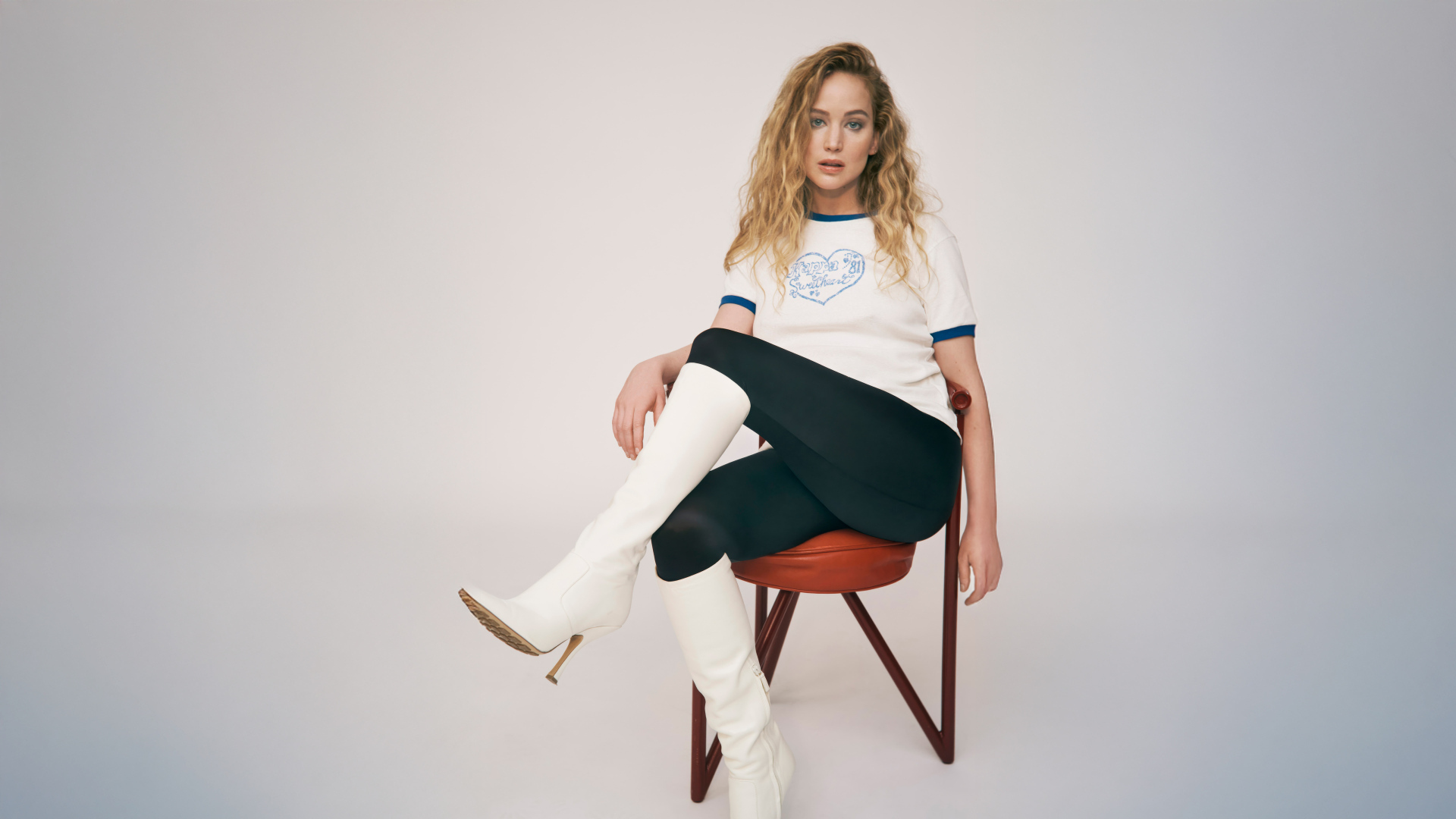 Актриса Дженнифер Лоуренс сидит на стуле на сером фоне