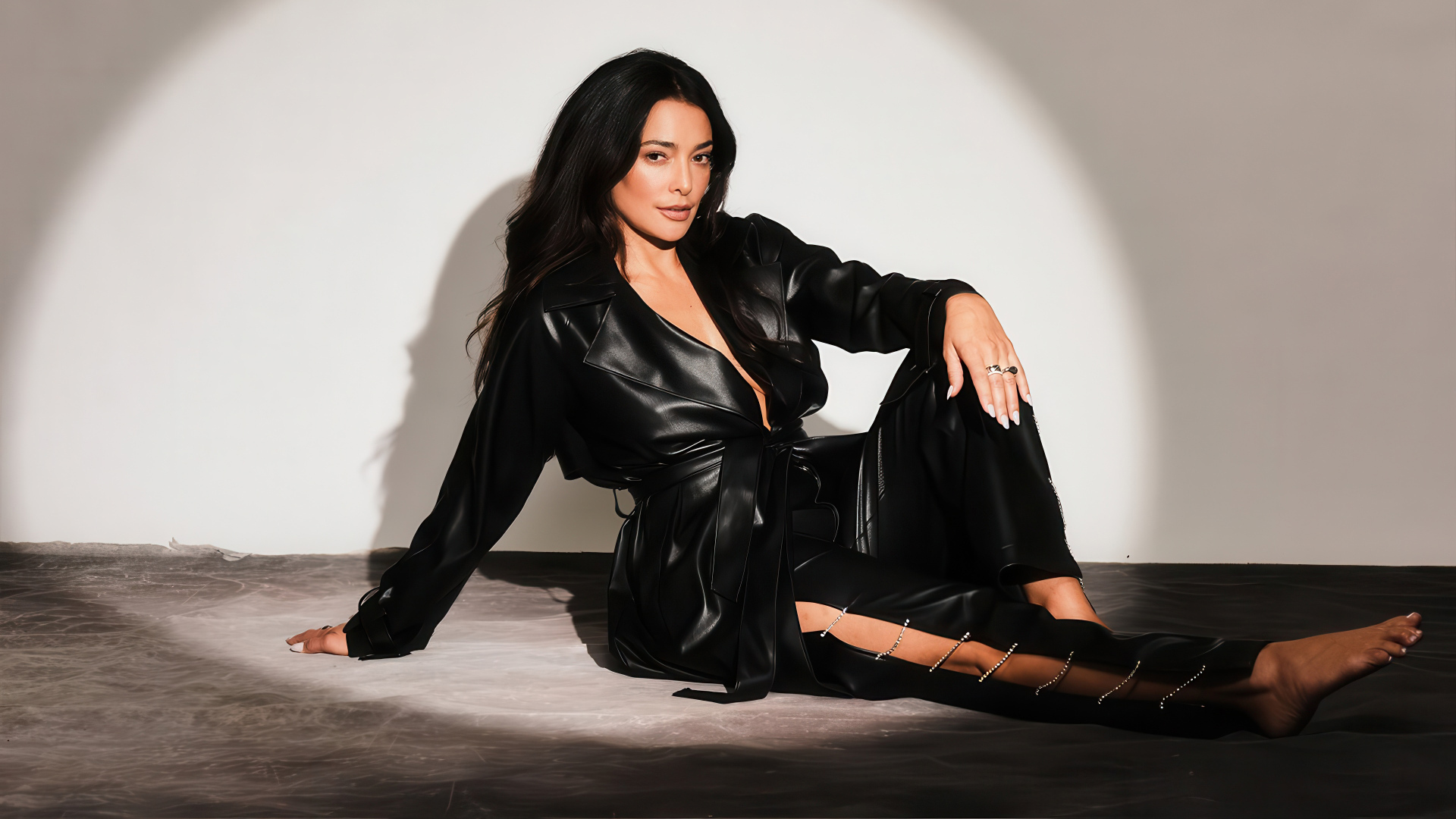 Актриса Натали Мартинес в черном кожаном костюме на фоне серой стены