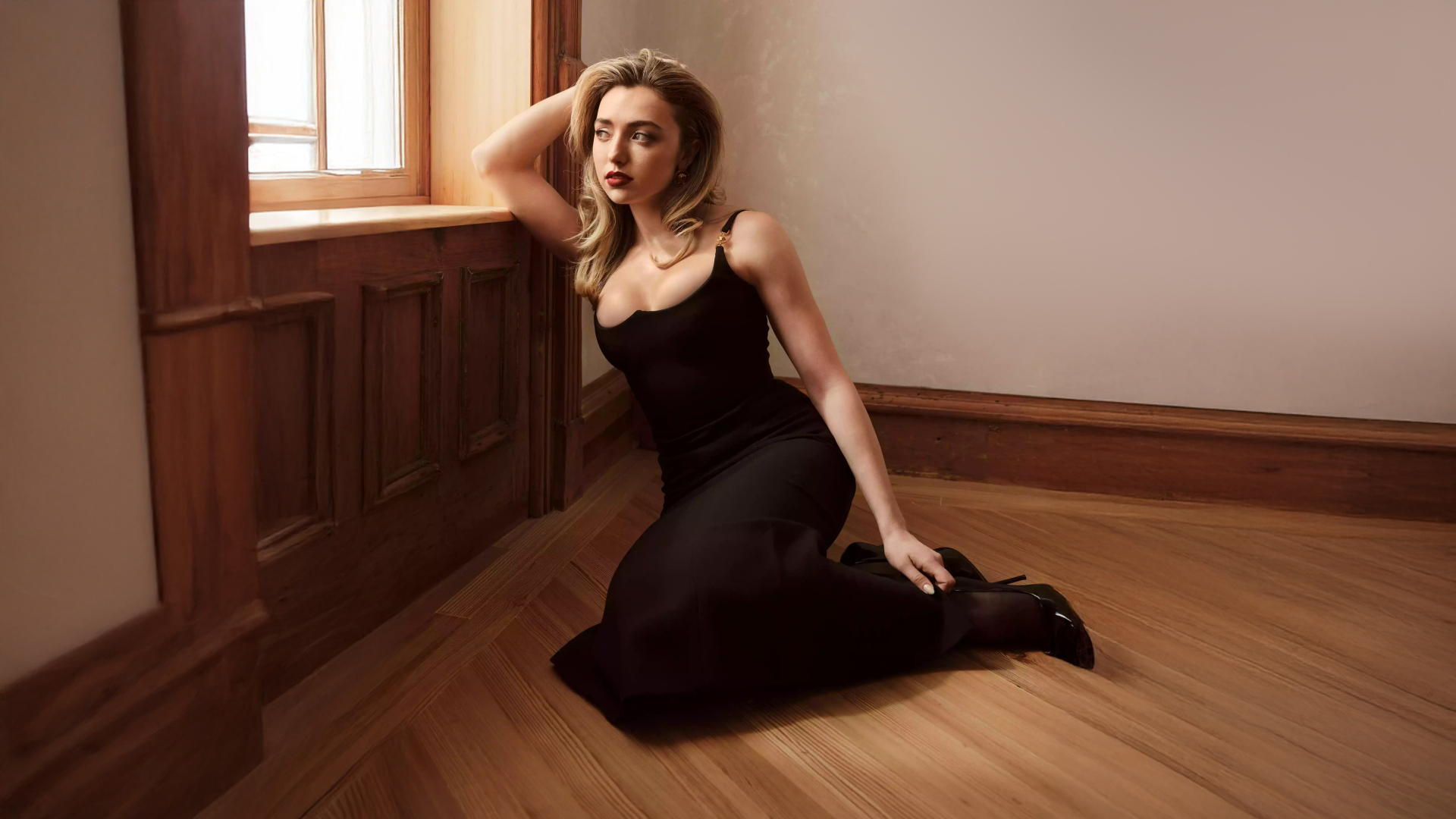 Актриса Пейтон Рой Лист в черном платье сидит на полу у окна