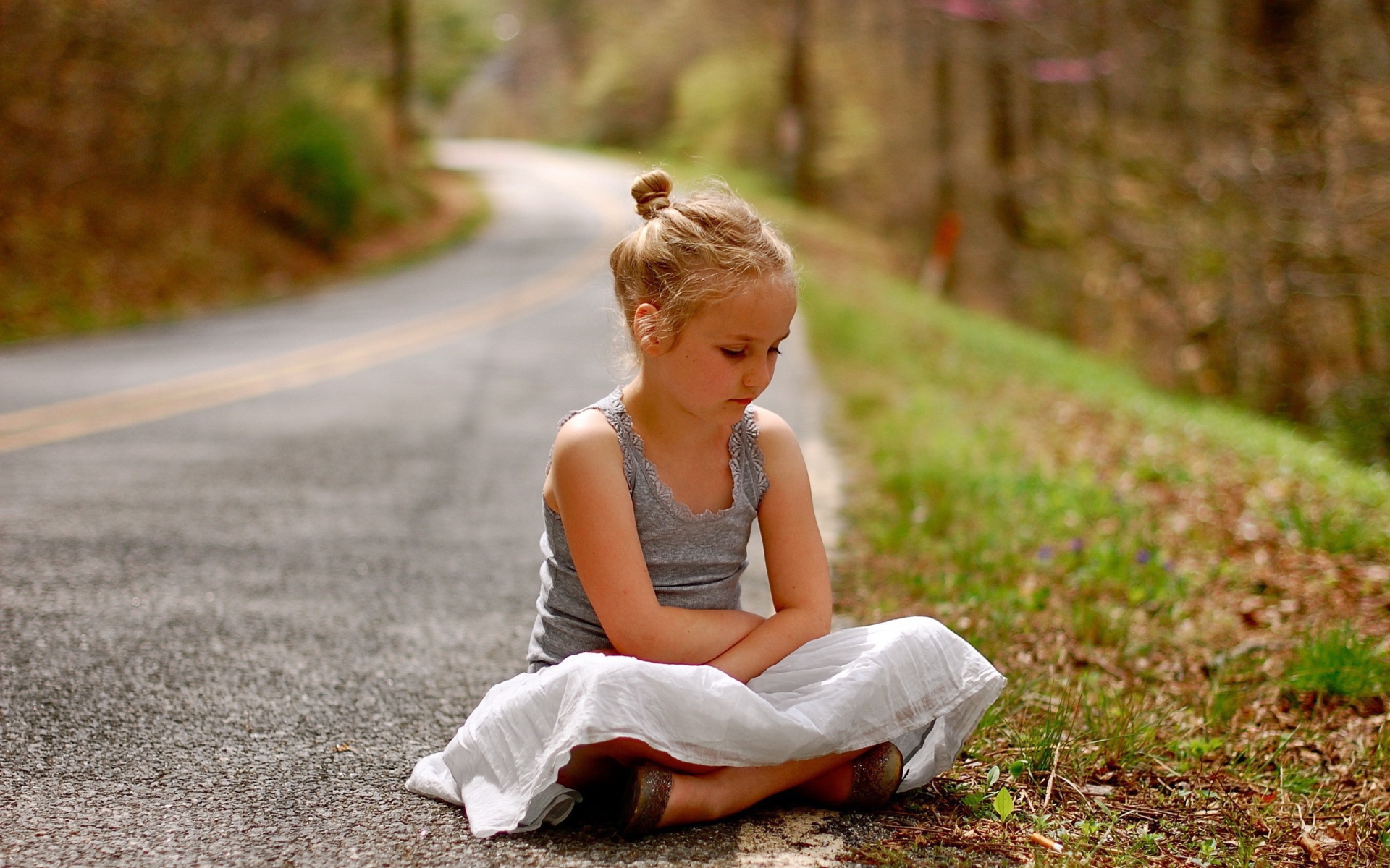 Девочка сидит на обочине дороги