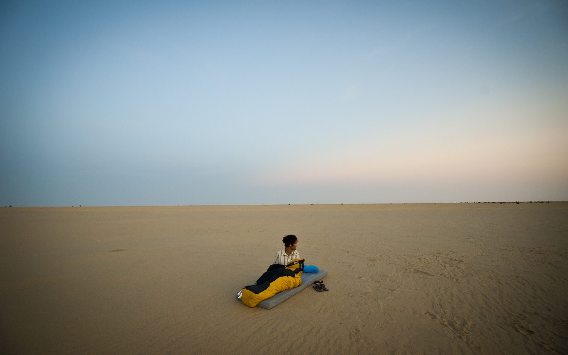 Мужчина на матрасе на пляже