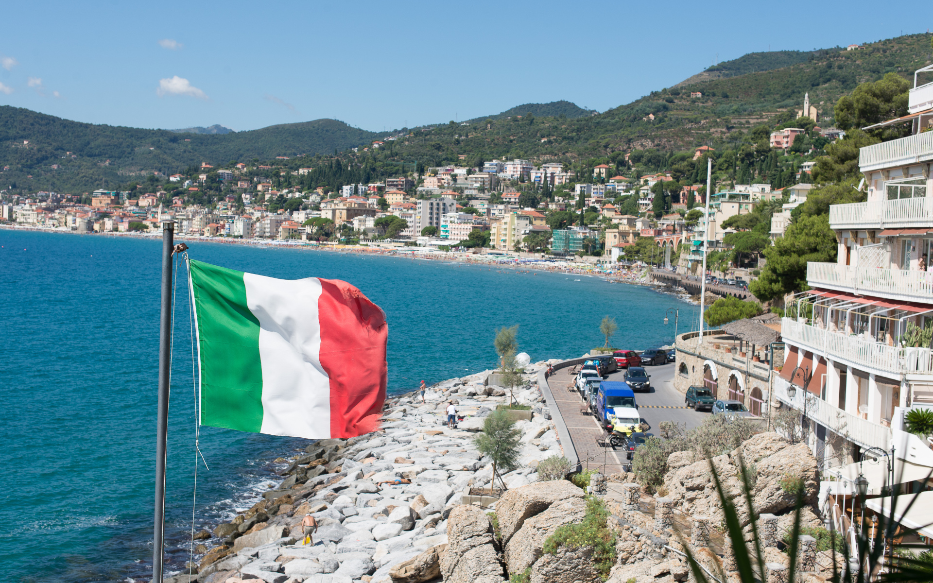 Флаг на фоне пляжа на курорте Алассио, Италия