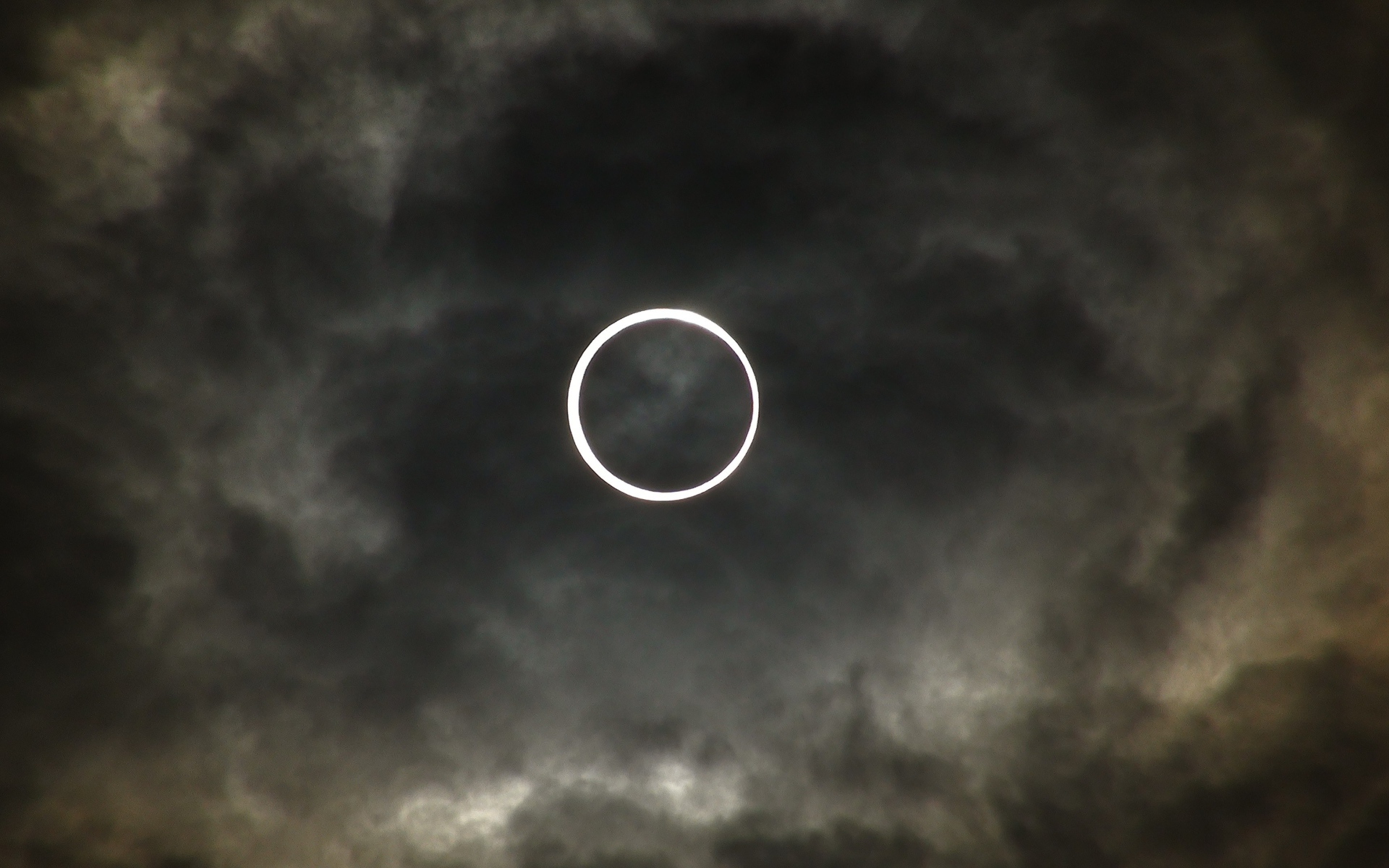 Белый круг на фоне темных облаков