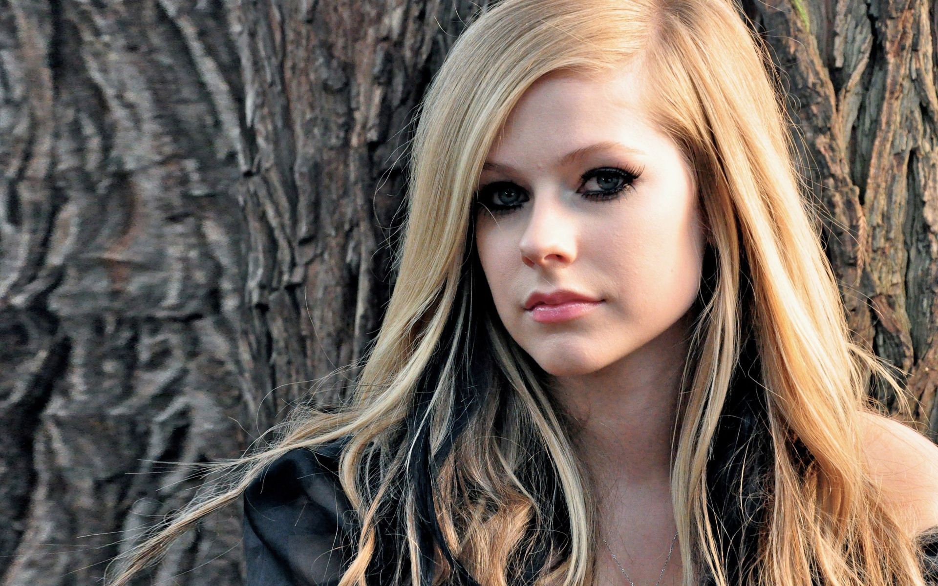 Блондинка Аврил Лавин на фоне коры дерева