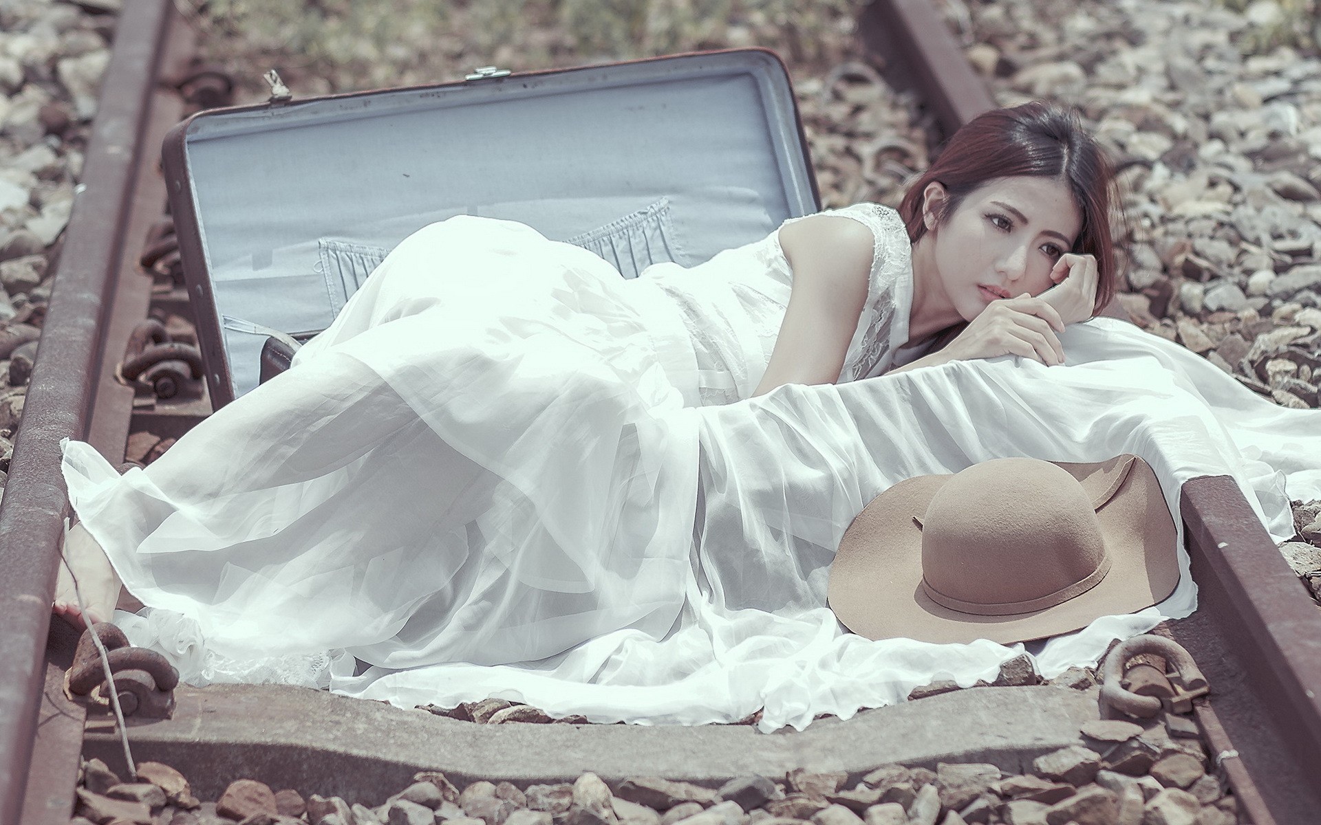 Девушка лежит в чемодане на рельсах