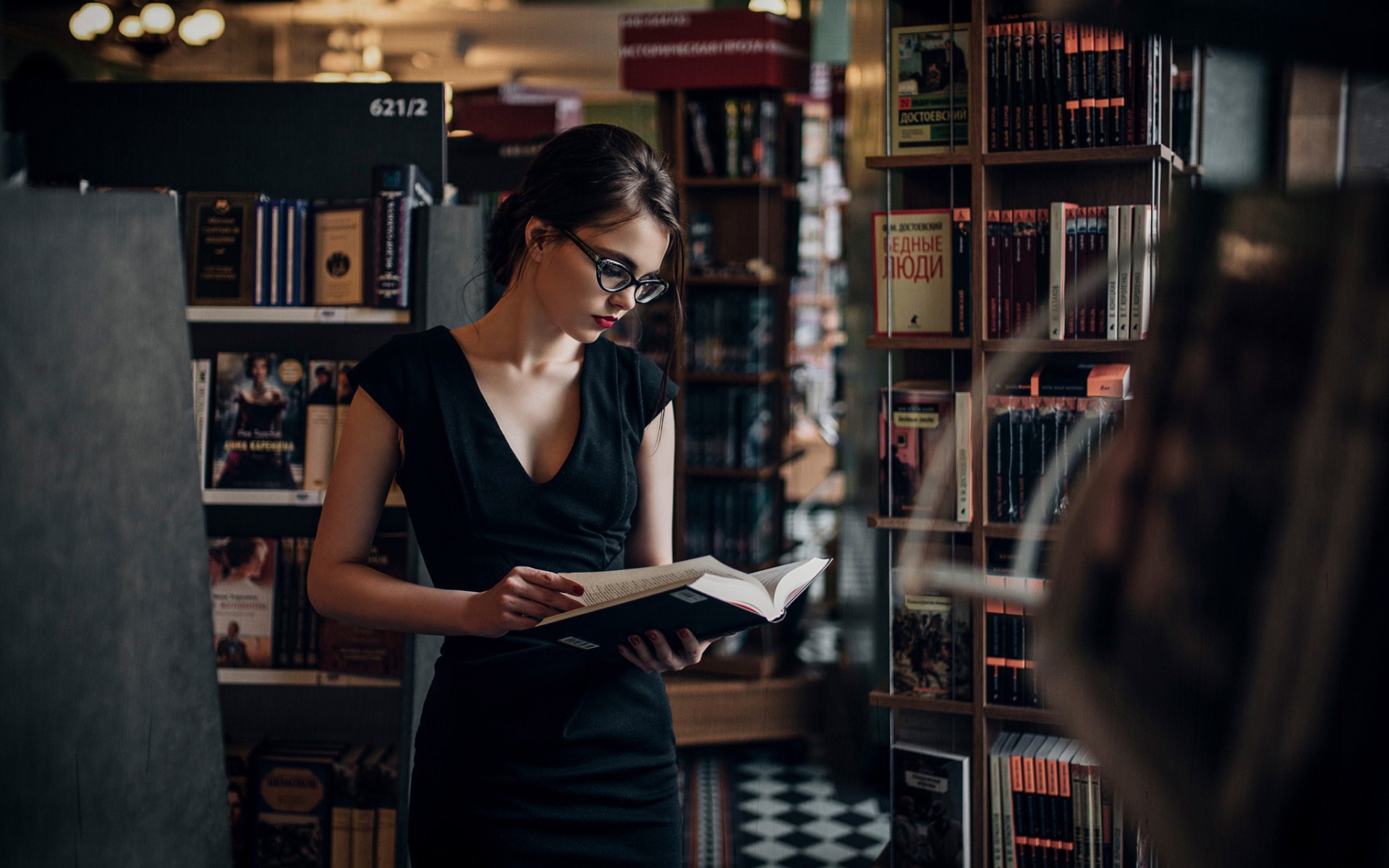 Девушка читает среди книжных полок