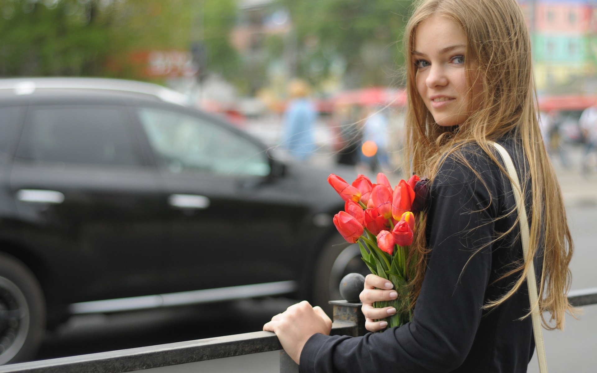 Девушка с букетом тюльпанов стоит у забора