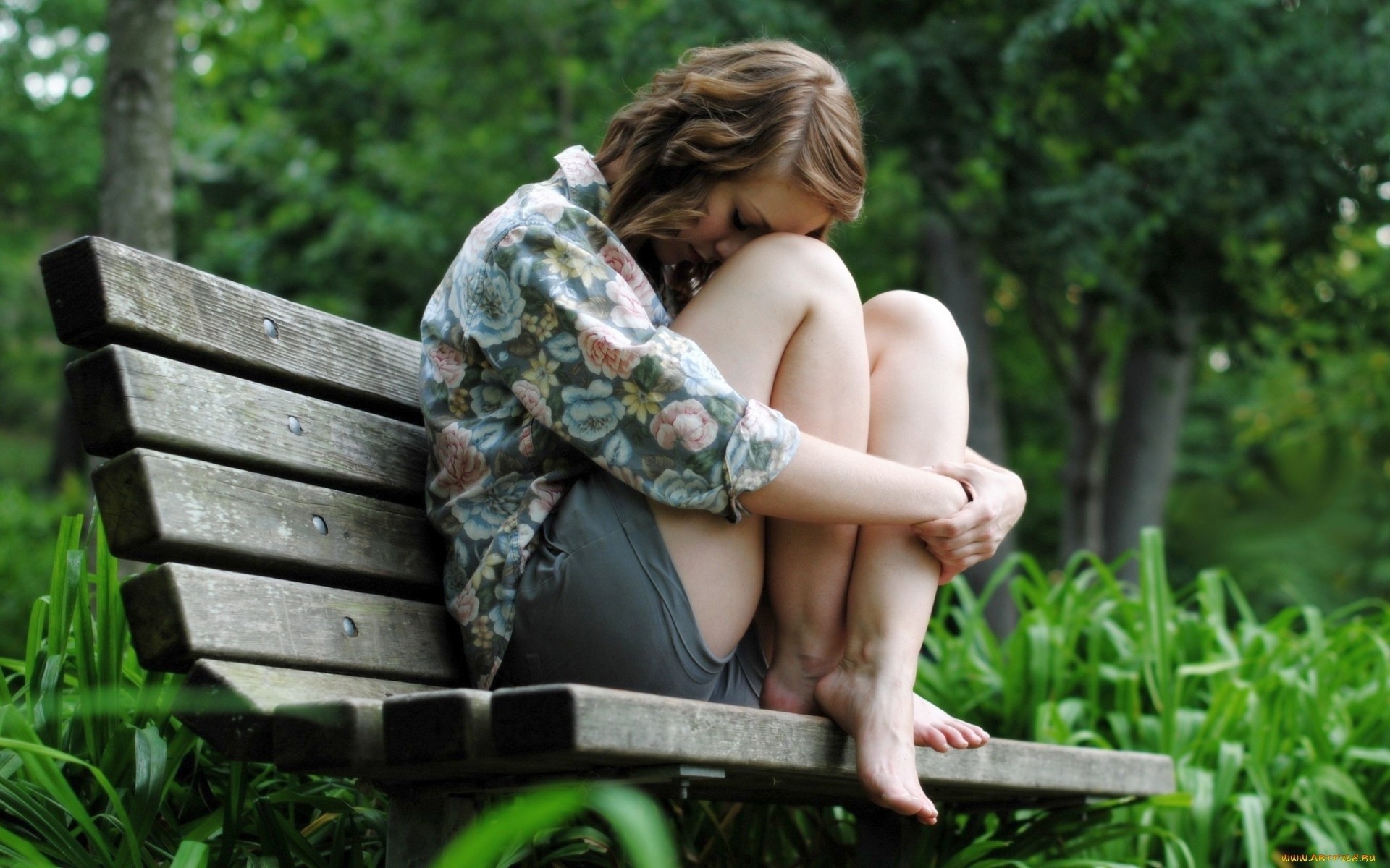 Девушка грустит сидя на скамье