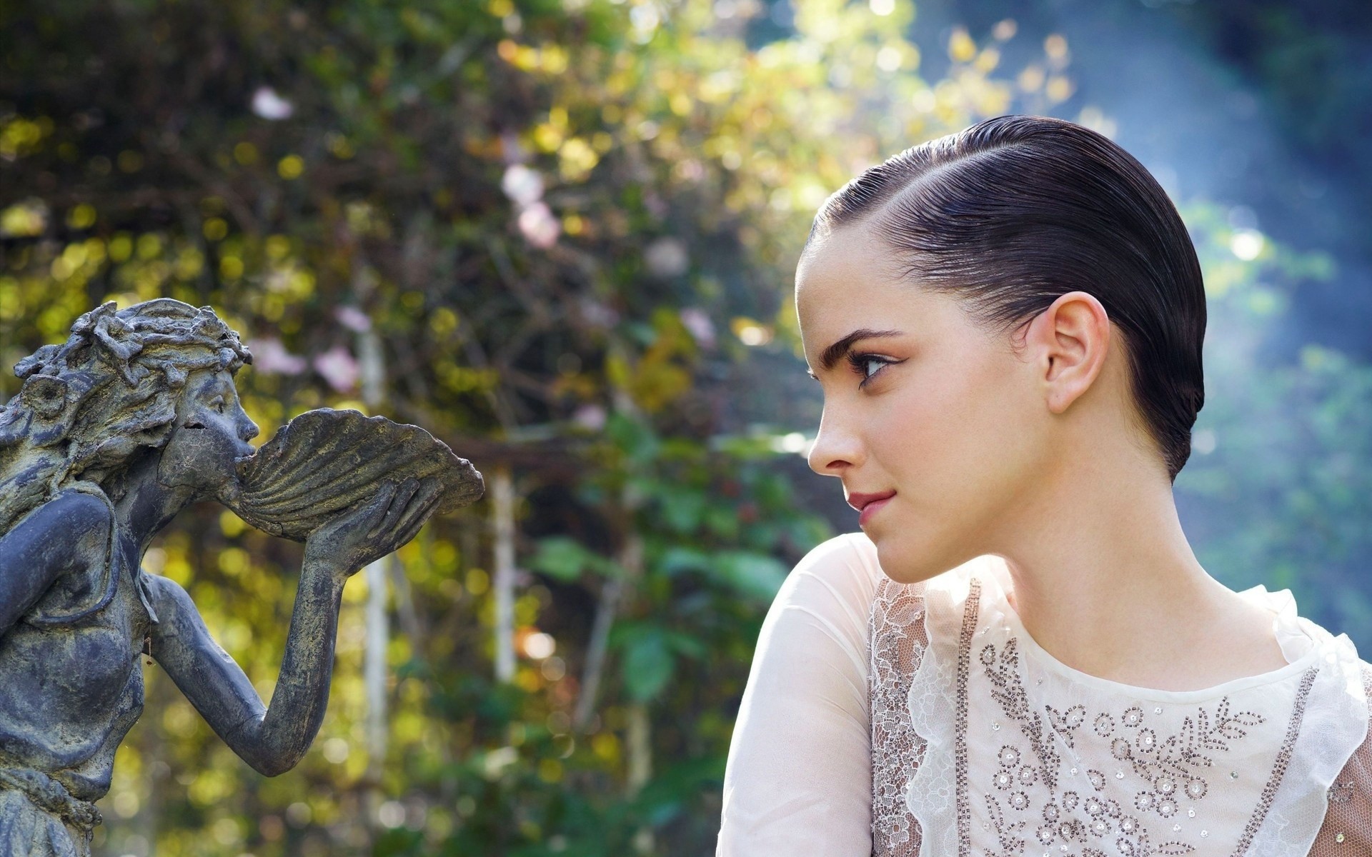 Девушка смотрит на скульптуру в саду