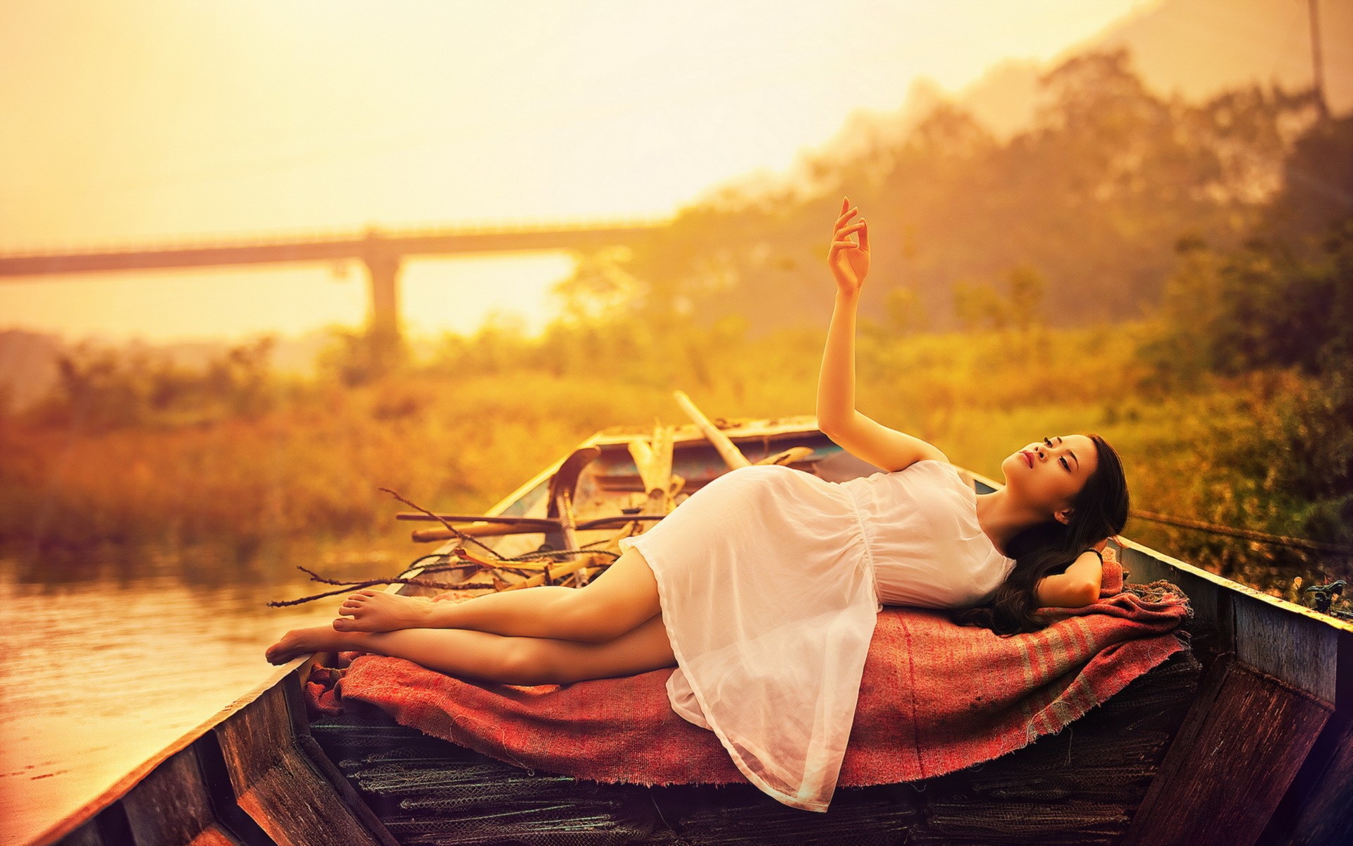 Азиатская модель в белом платье лежит в лодке