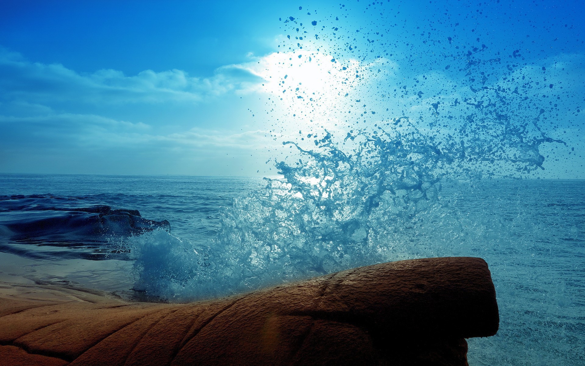Голубая волна разбилась о камень на берегу