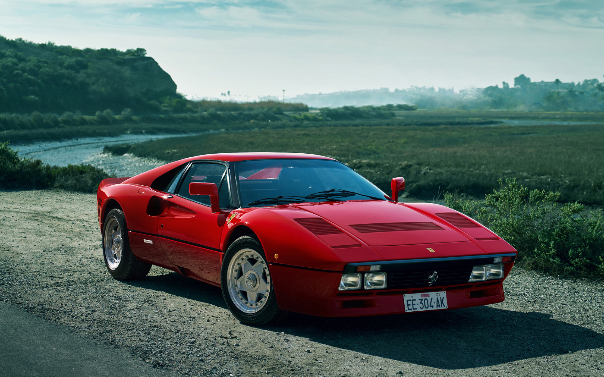 Красный быстрый автомобиль Ferrari 288 GTO у реки