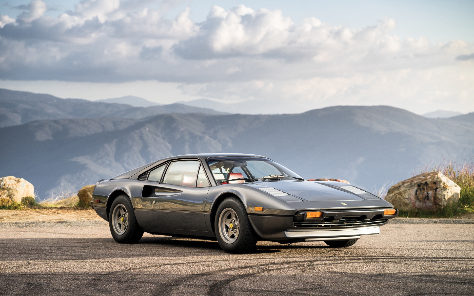 Суперкар Ferrari 308 gts серого цвета,   на фоне гор 