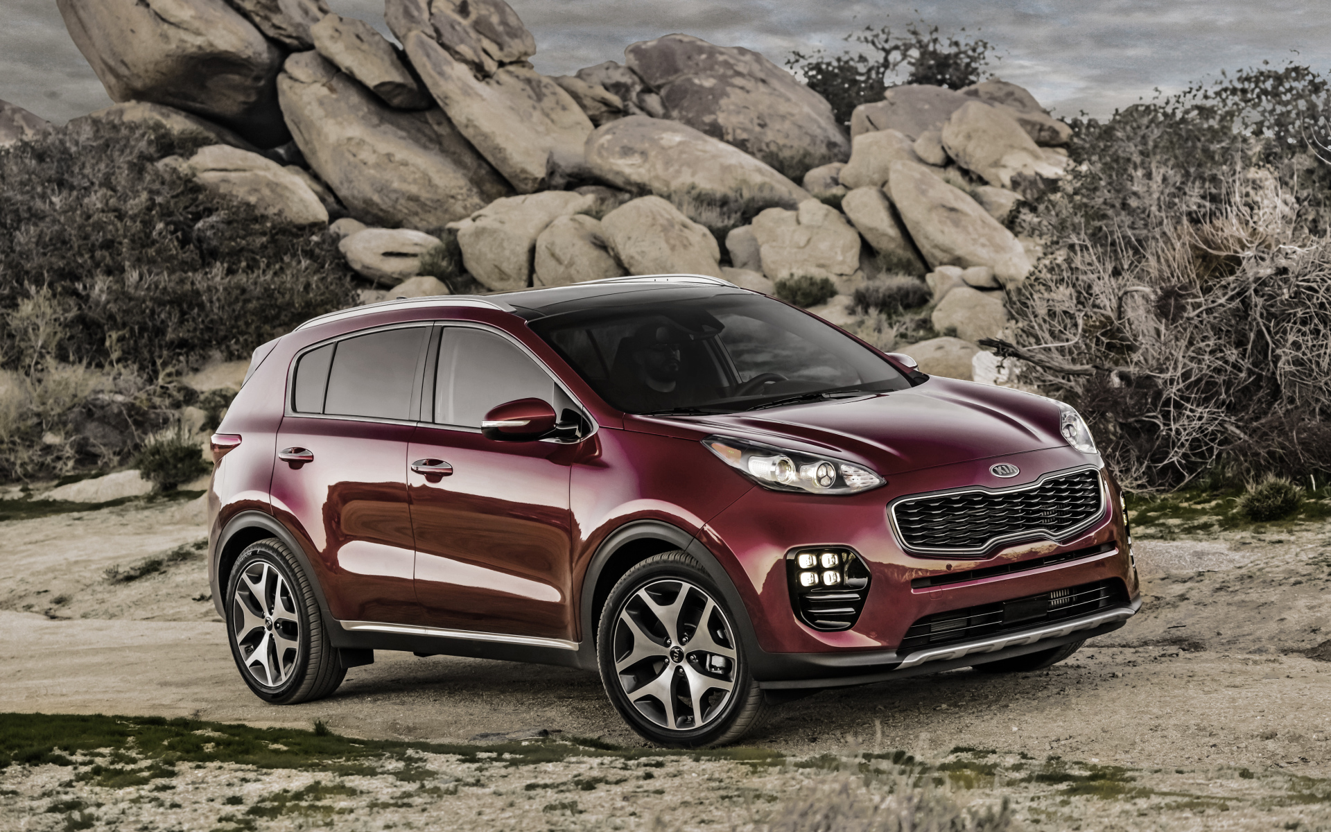 Стильный бордовый внедорожник Kia Sportage на фоне больших камней