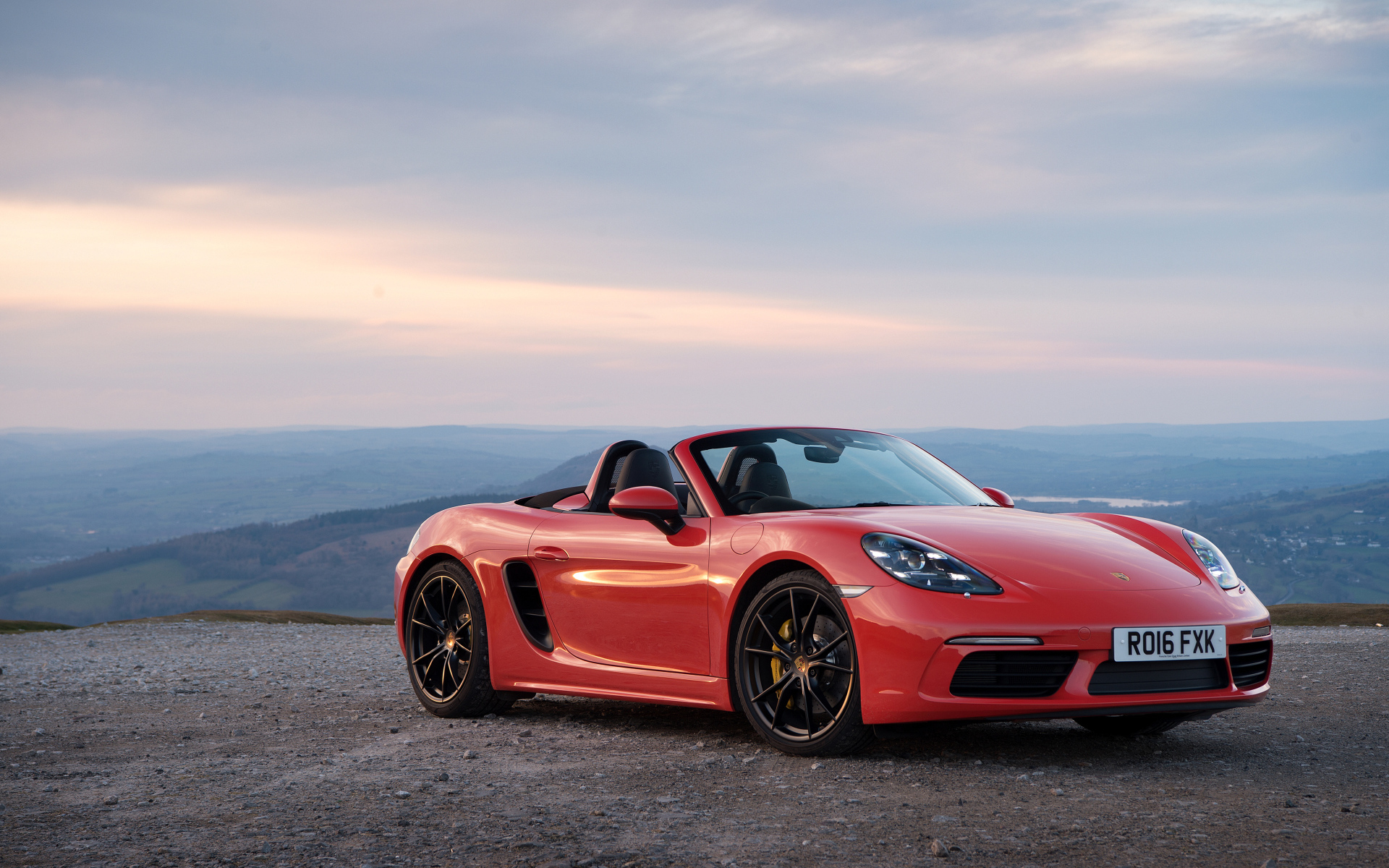 Красный автомобиль кабриолет Porsche 718 Boxster на фоне горизонта 