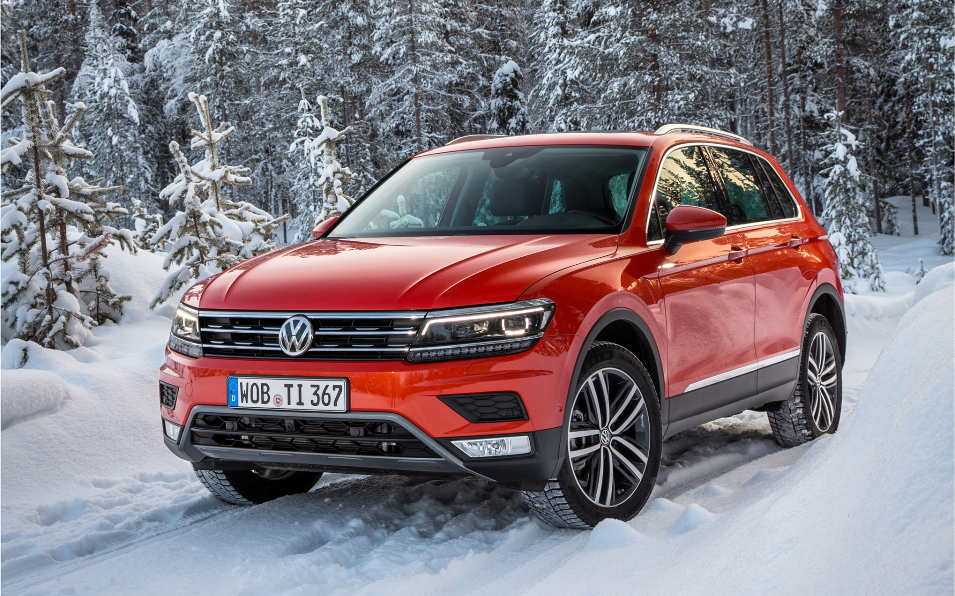 Красный Volkswagen Tiguan 2017 года в заснеженном лесу 