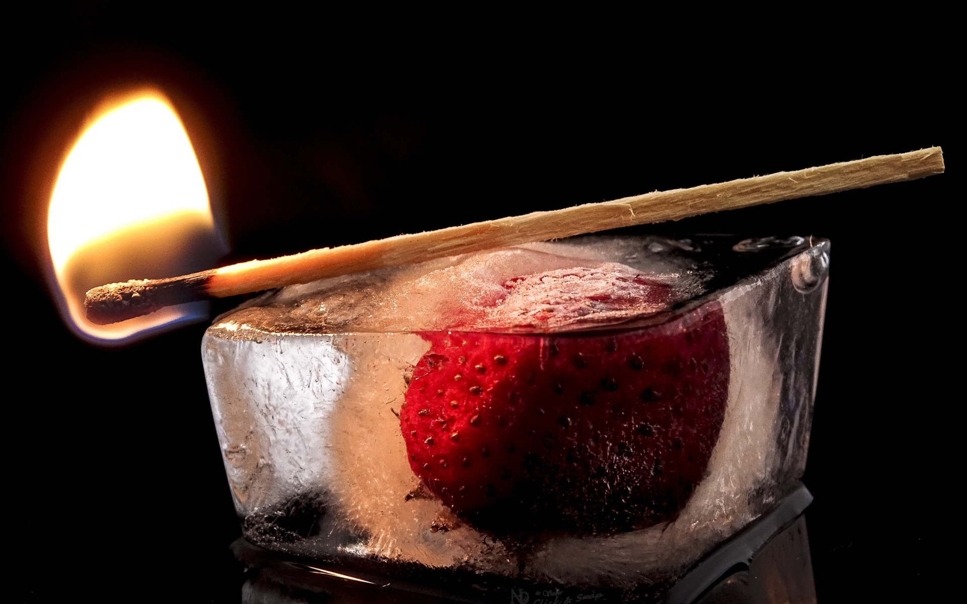 Зажженная спичка на кусочке льда с клубникой 