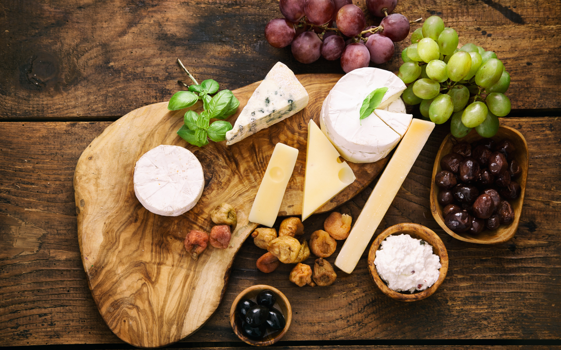 Кусочки сыра с виноградом и оливками на столе