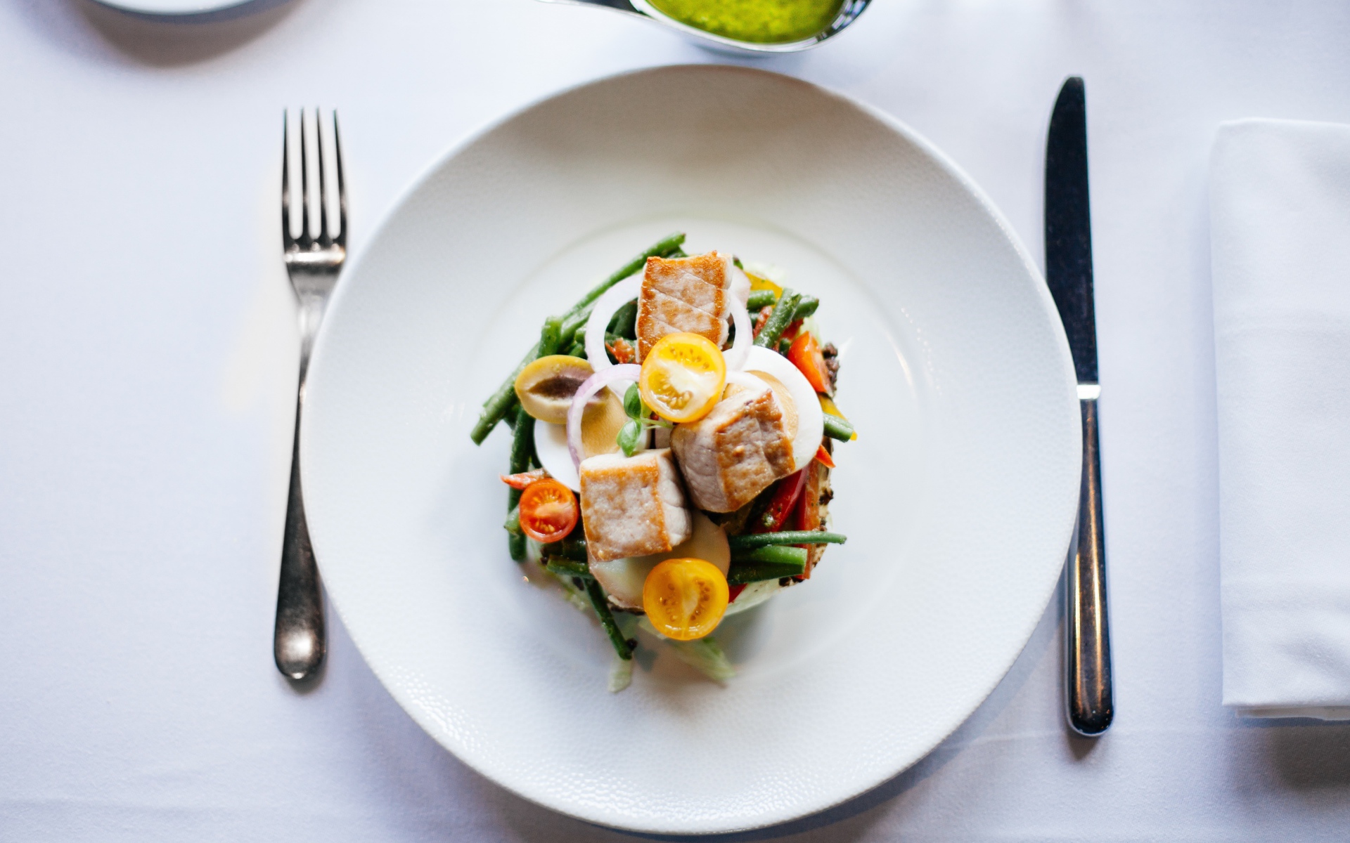 Овощной салат на белой тарелке со столовыми приборами