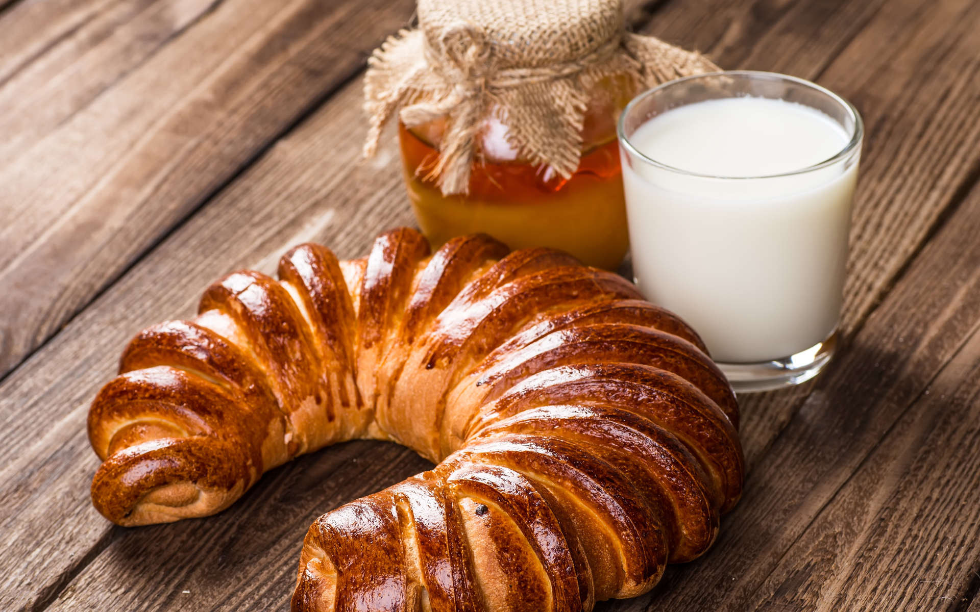 Свежая выпечка на столе с медом и стаканом молока