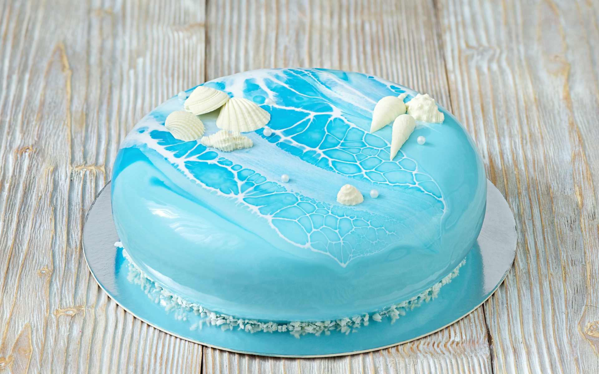 Глянцевый торт голубого цвета украшен сахарными ракушками