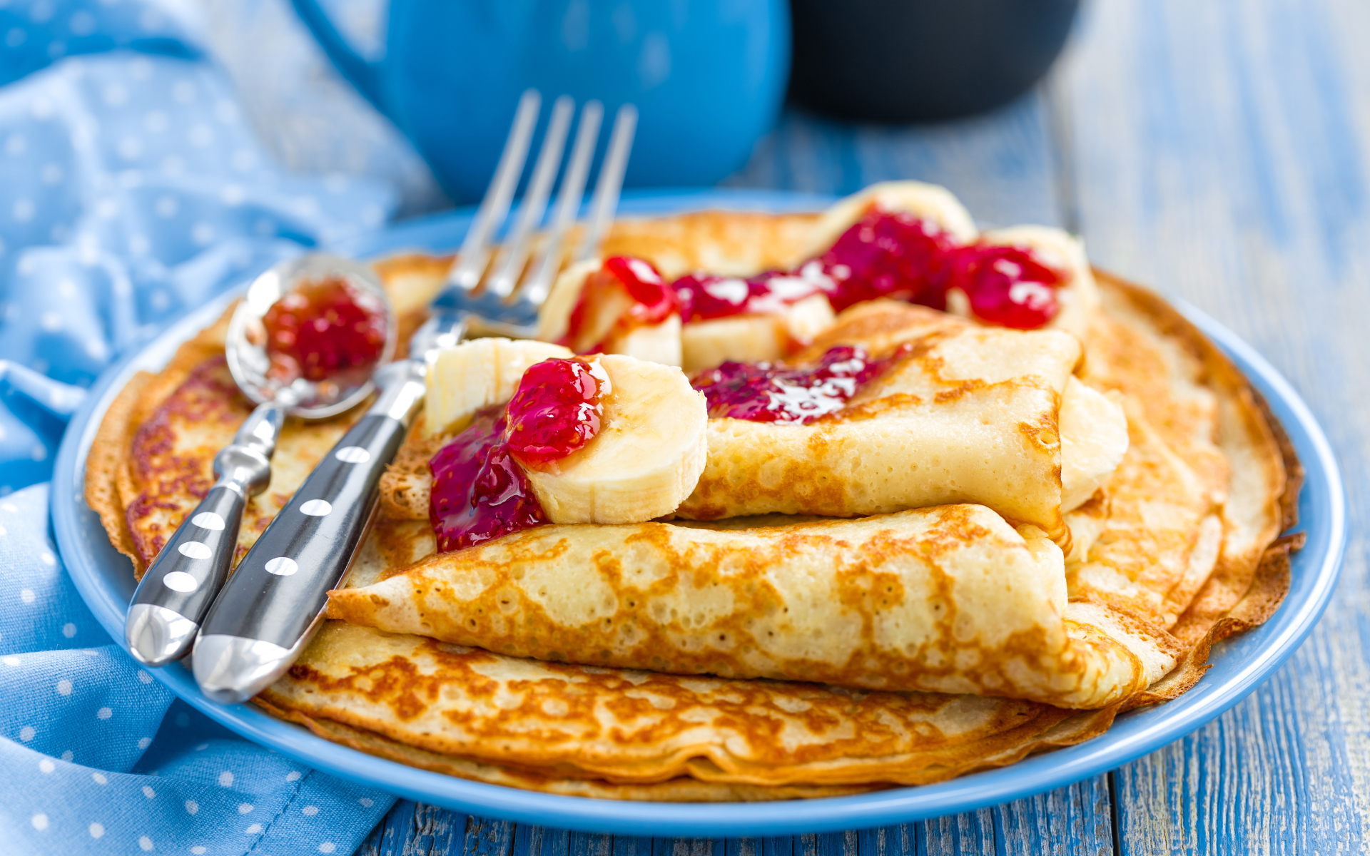 Блины с клубничным джемом и бананами на блюде 