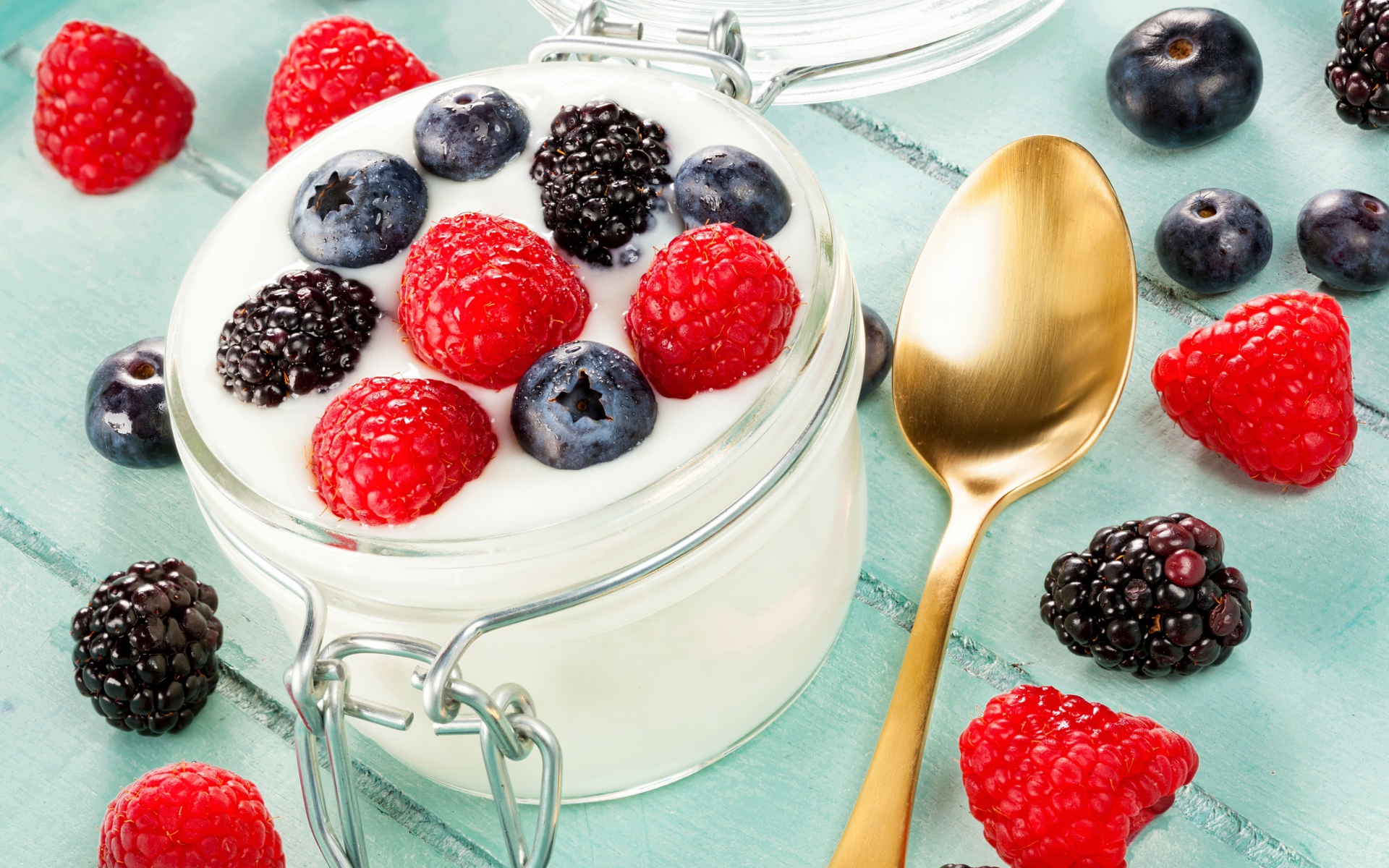 Йогурт со свежими ягодами малины, черники и ежевики в стеклянной банке на завтрак