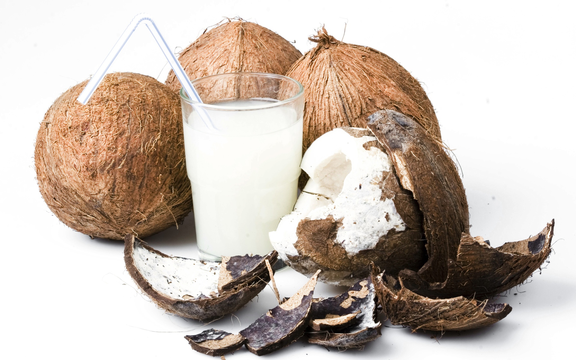 Кокосовое молоко в стакане и кокосы на белом фоне