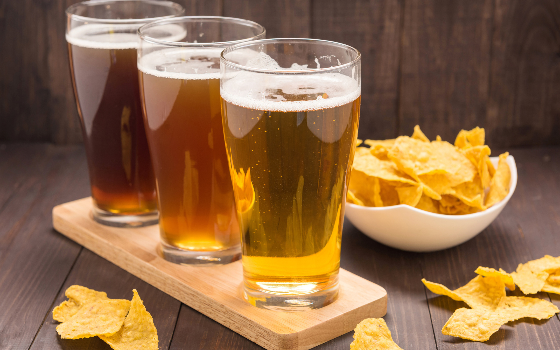Три стакана пива на столе с чипсами