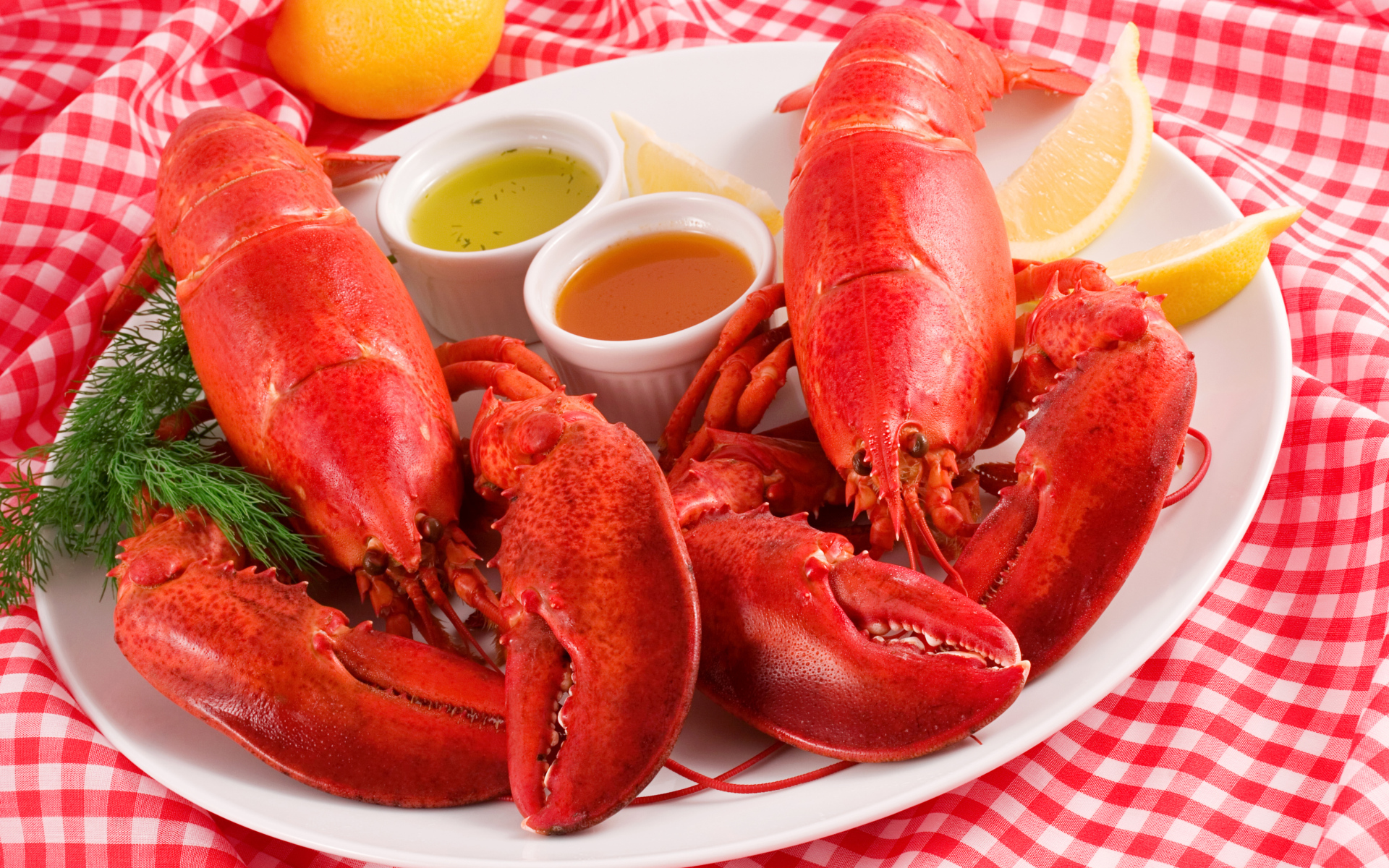 Два вареных омара на тарелке с соусом