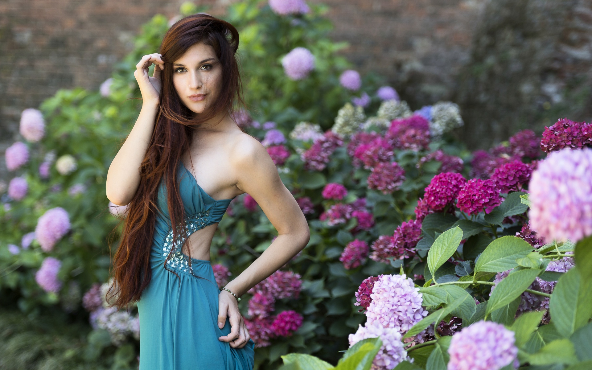 Красивая девушка модель в зеленом платье рядом с цветами гортензии