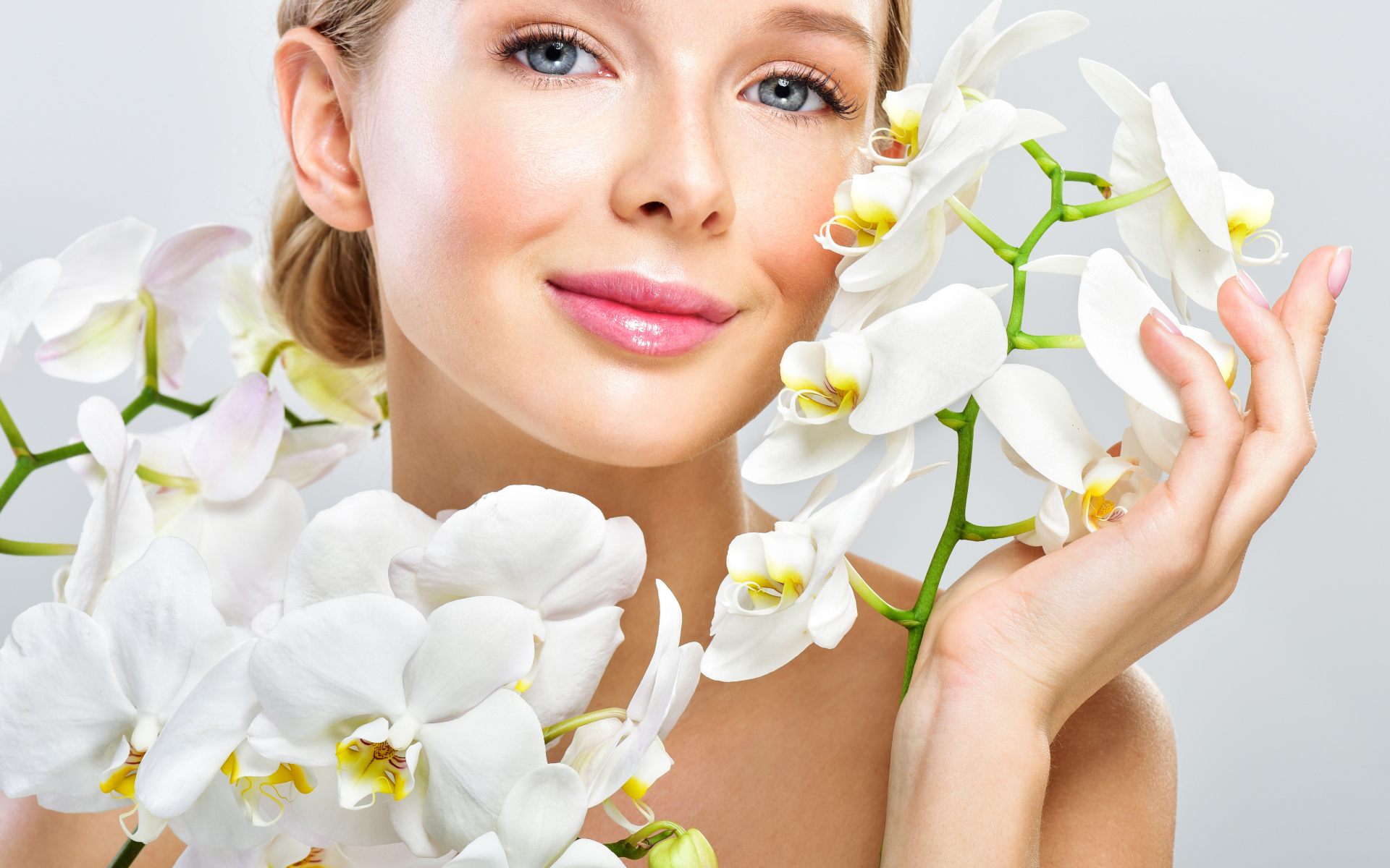 Нежная голубоглазая девушка с цветами орхидеи в руках