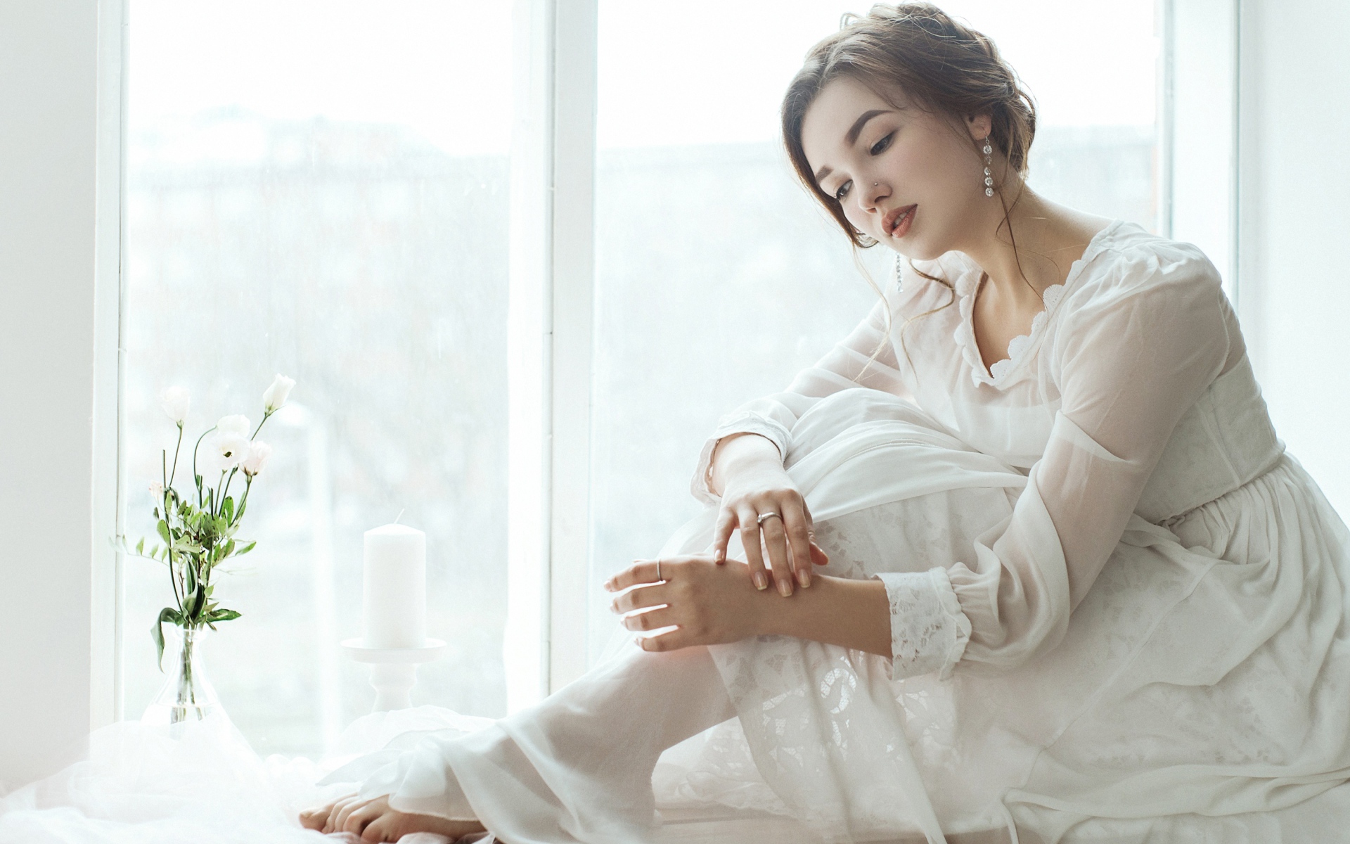 Молодая грустная девушка в белом платье у окна