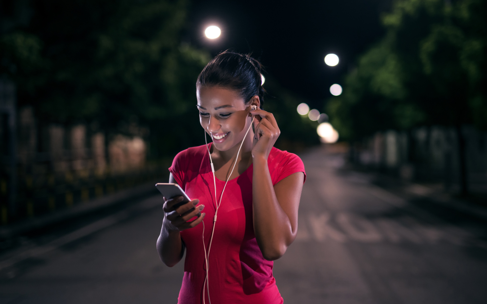 Молодая улыбающаяся девушка в наушниках с телефоном в руках