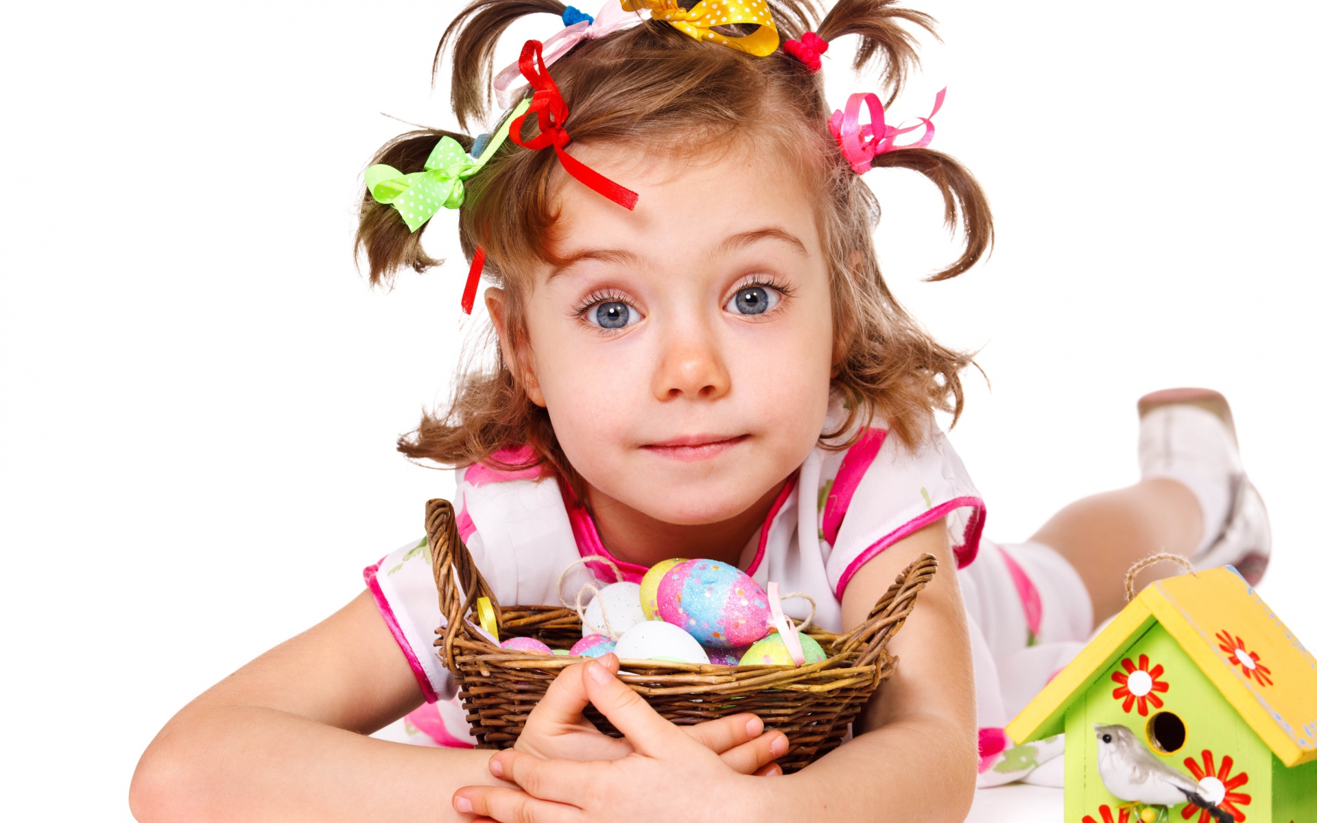 Little girl with a basket of Easter eggs on a white background