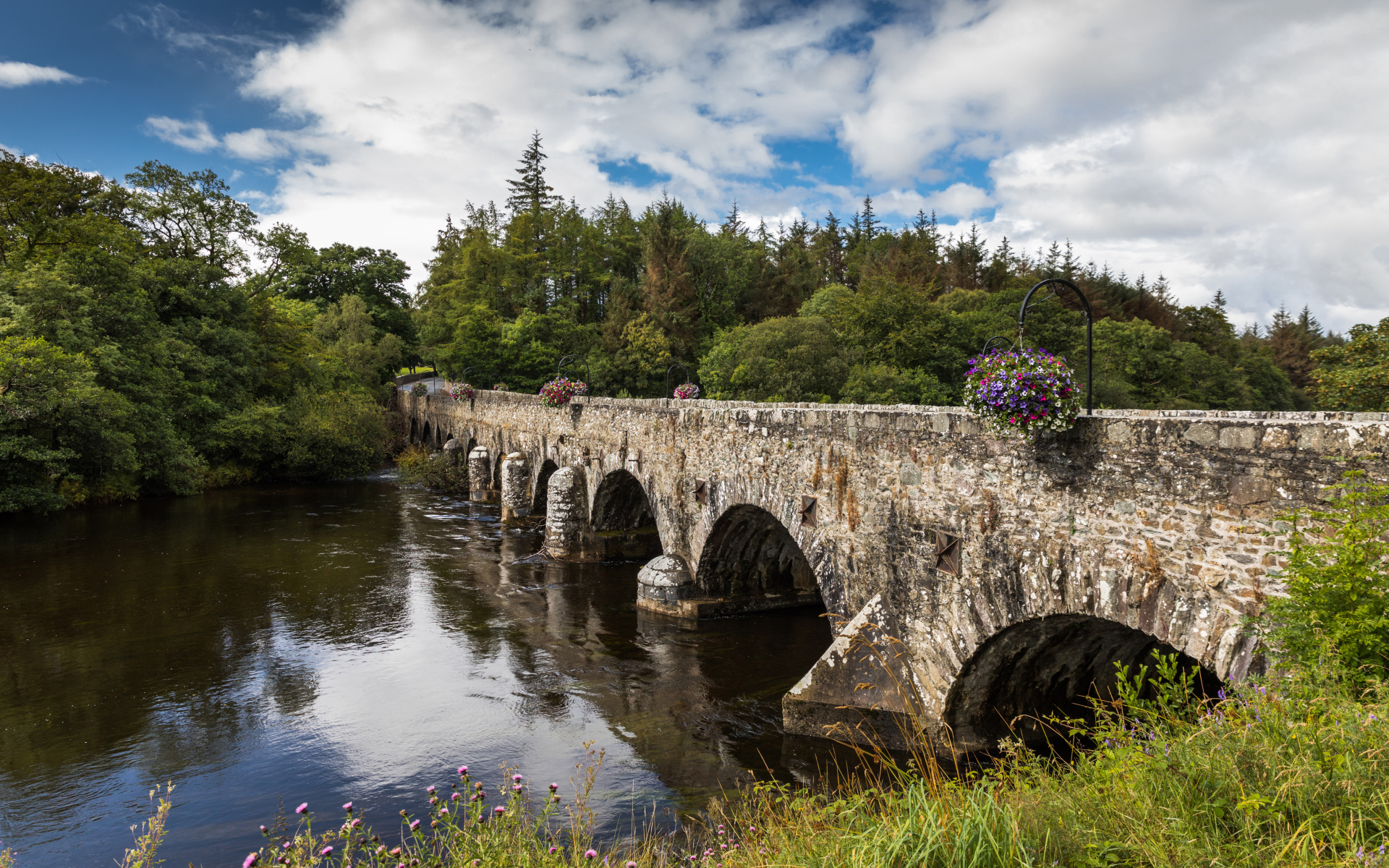 Мост через реку у леса на фоне красивого голубого неба с белыми облаками. Ирландия