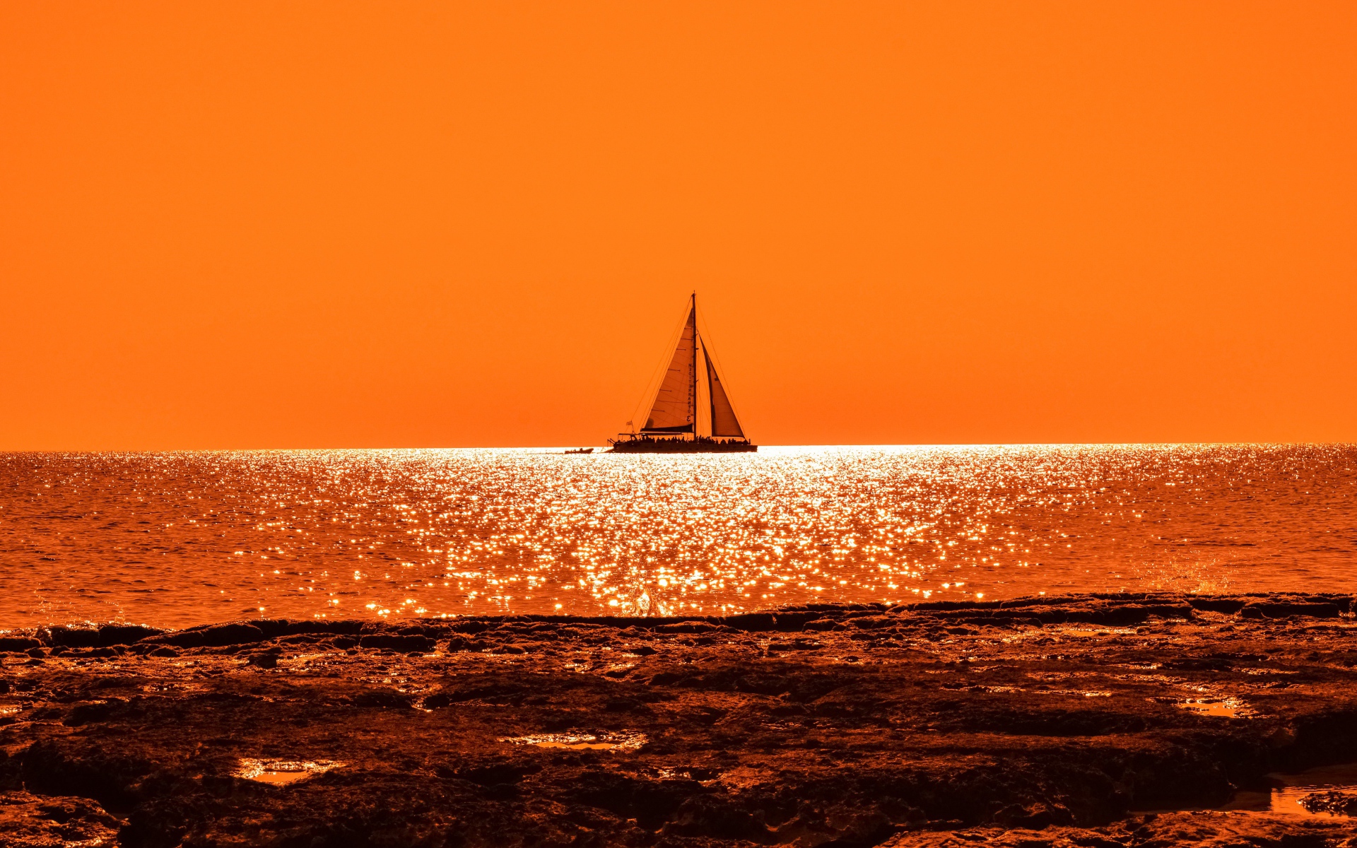 Парусная лодка на горизонте в океане на закате солнца