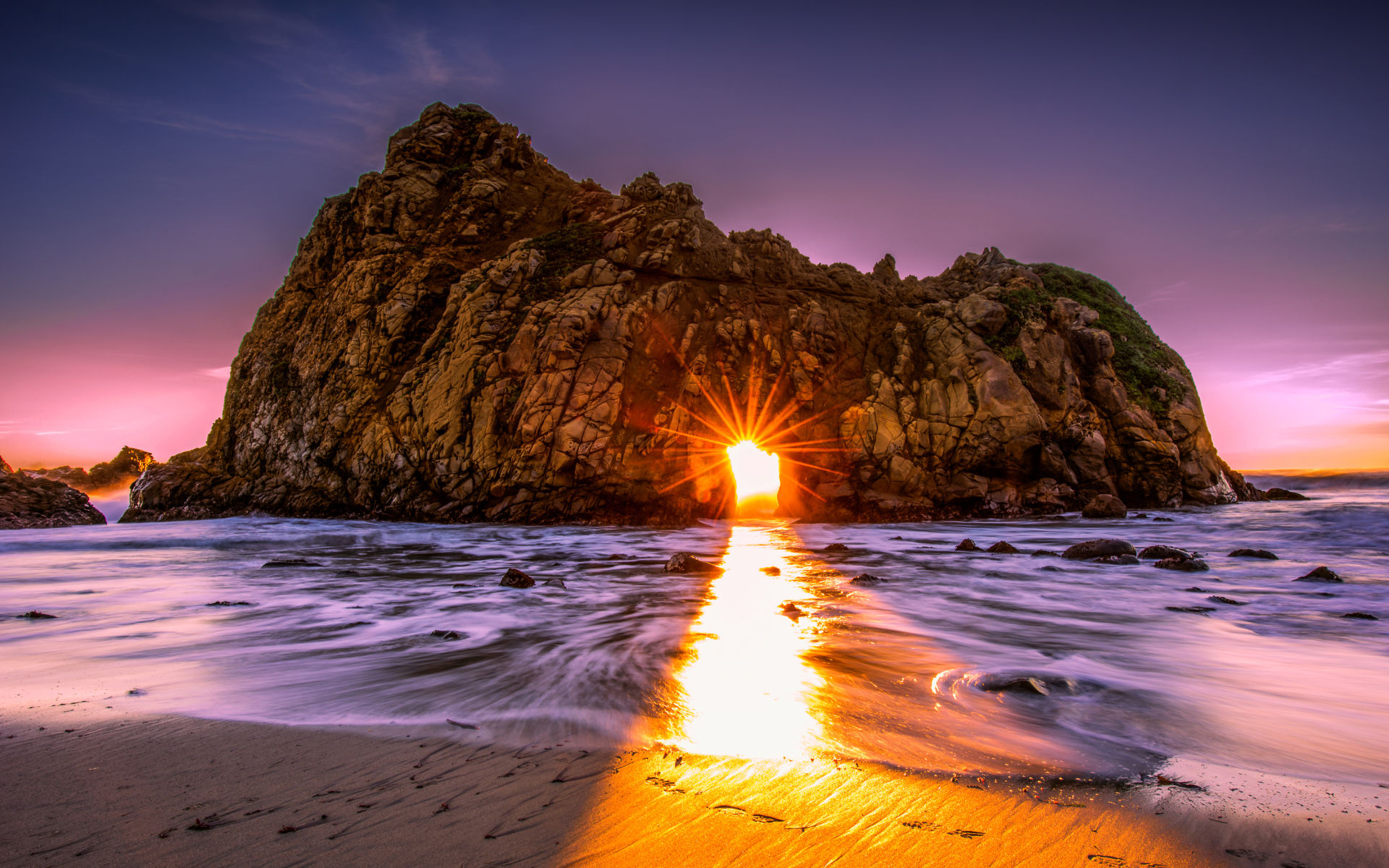 Лучи солнца пробиваются сквозь отверстие в скале  Pfeiffer Beach Big Sur, Калифорния  