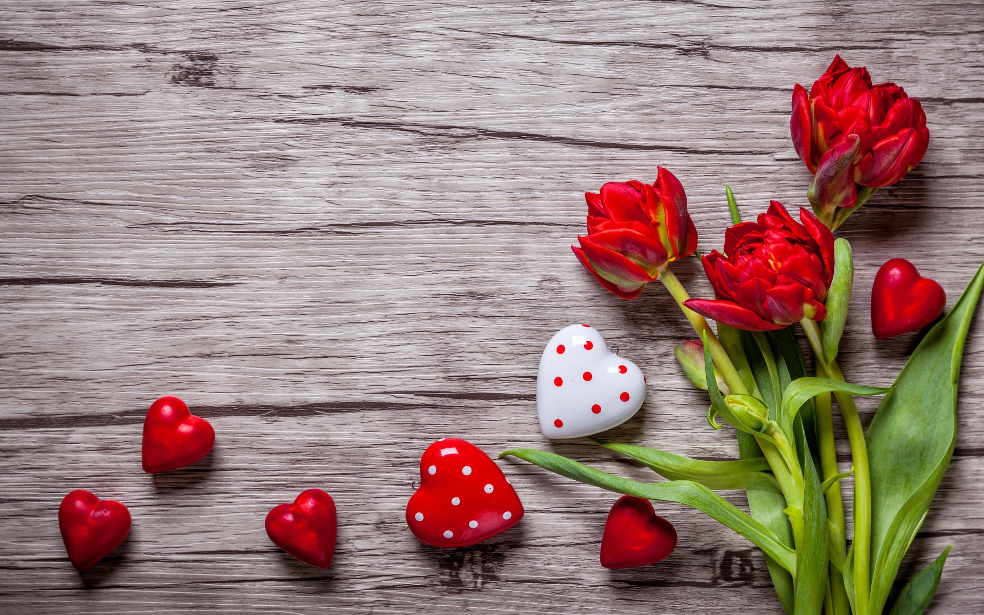 Красные красивые тюльпаны с сердечками на деревянной поверхности