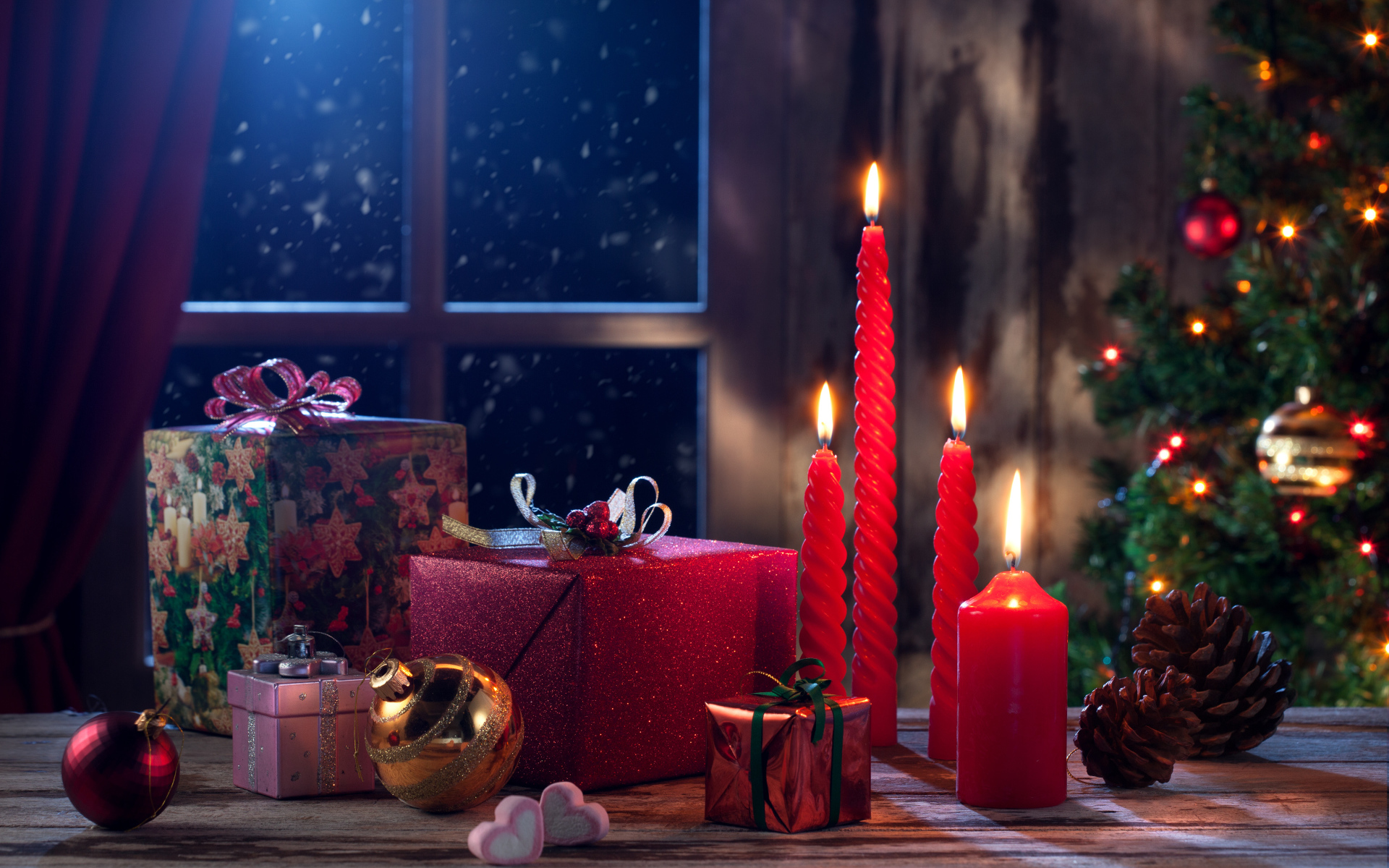 Зажженные красные свечи с подарками и игрушками на Новый год 2018