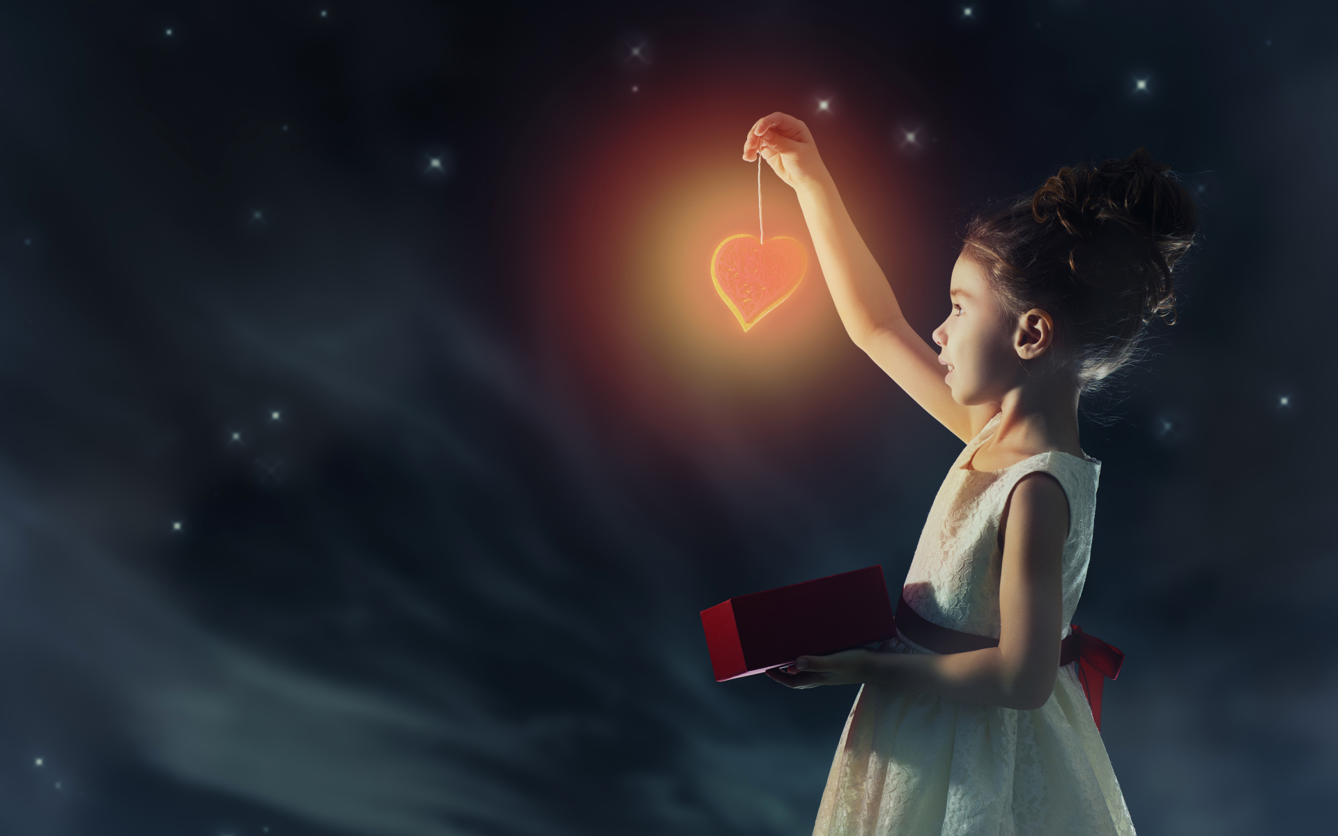 Девочка в красивом белом платье держит в руках сердечко