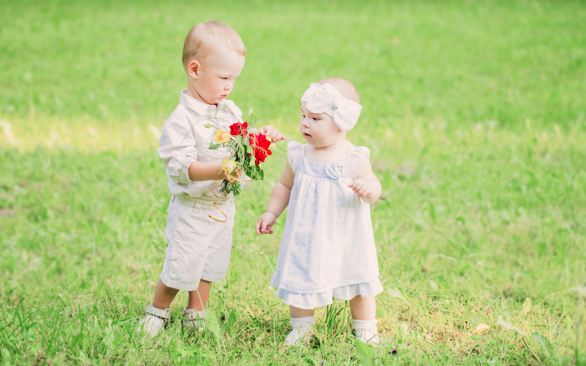 Маленький мальчик дарит букет полевых цветов девочке