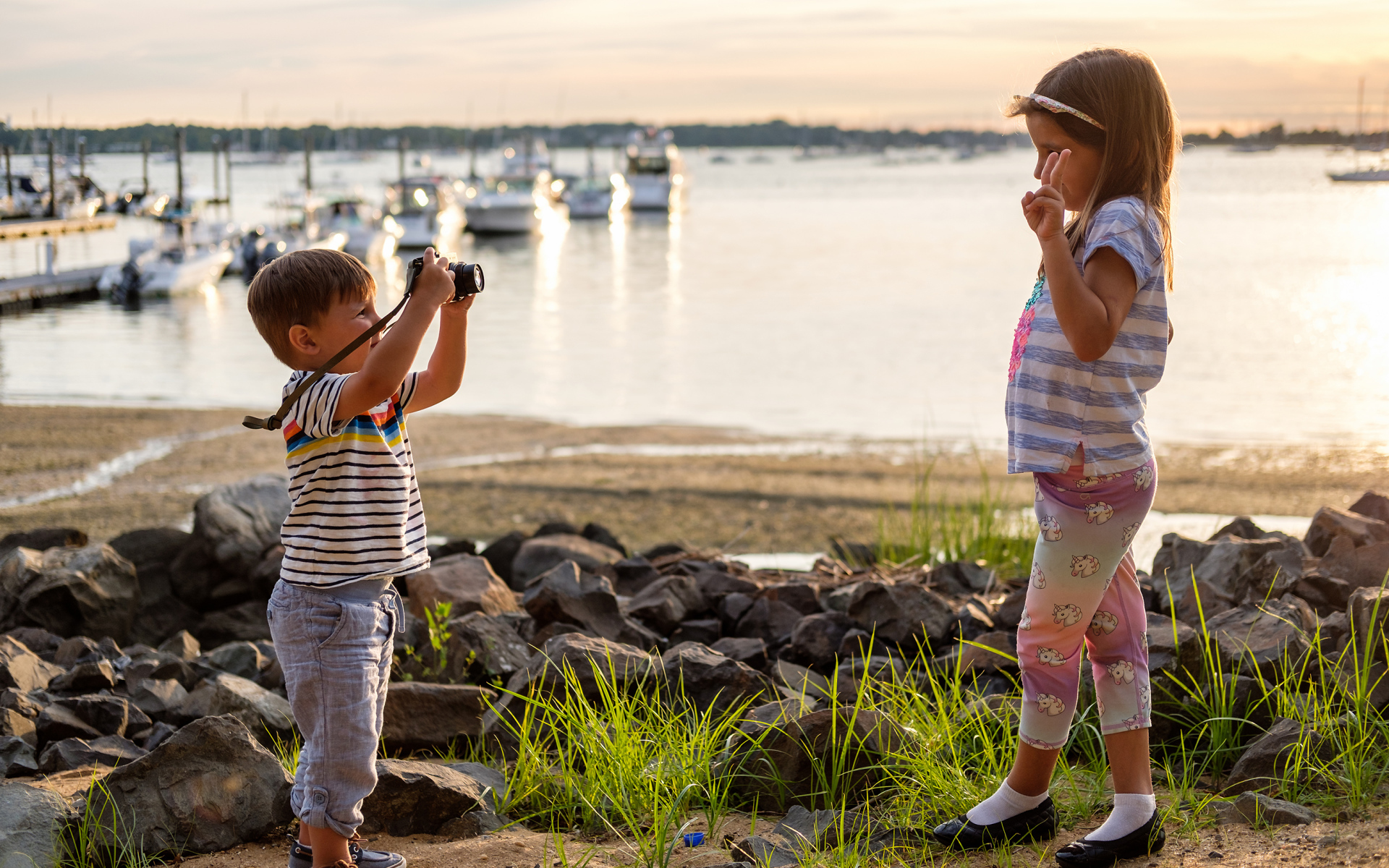 Маленький мальчик фотографирует девочку на берегу
