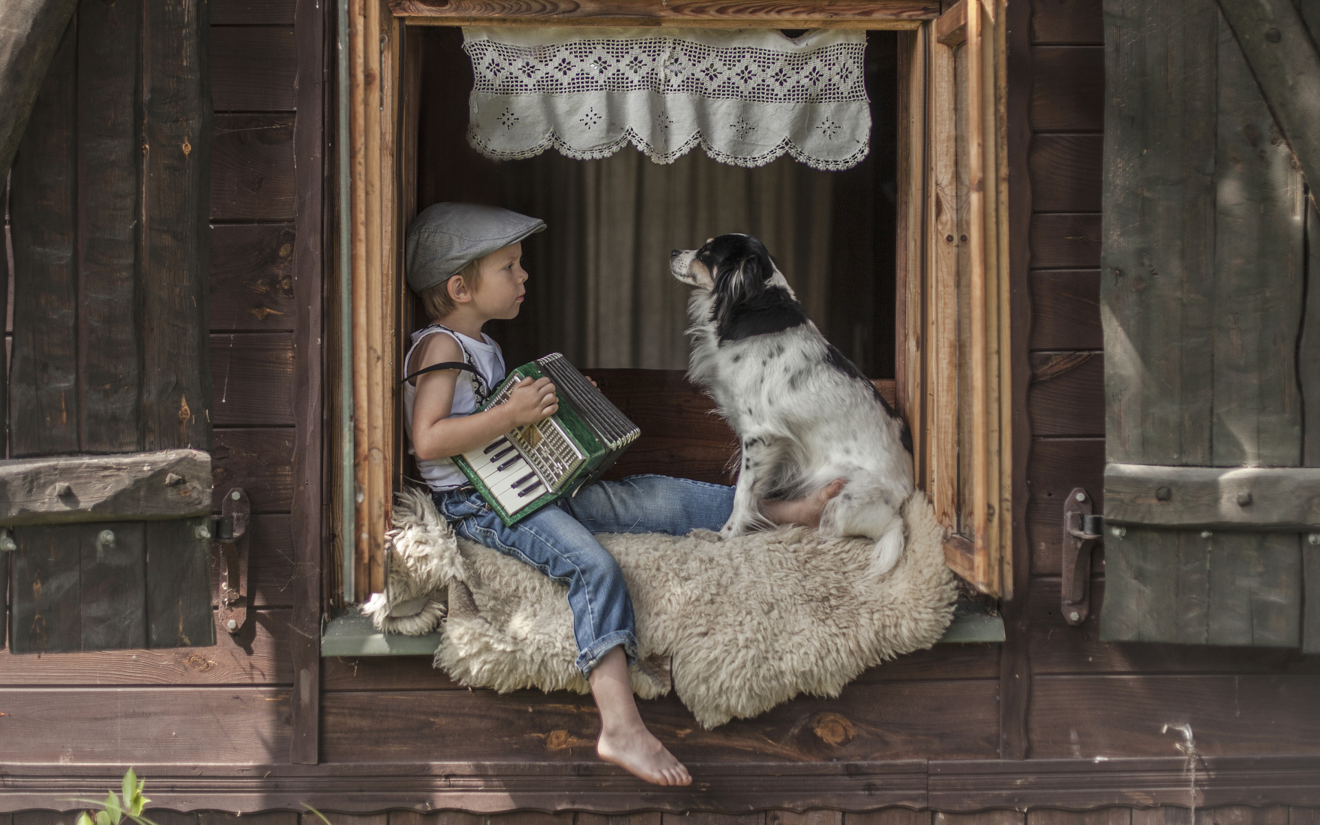 Маленький мальчик с гармошкой сидит на подоконнике с собакой